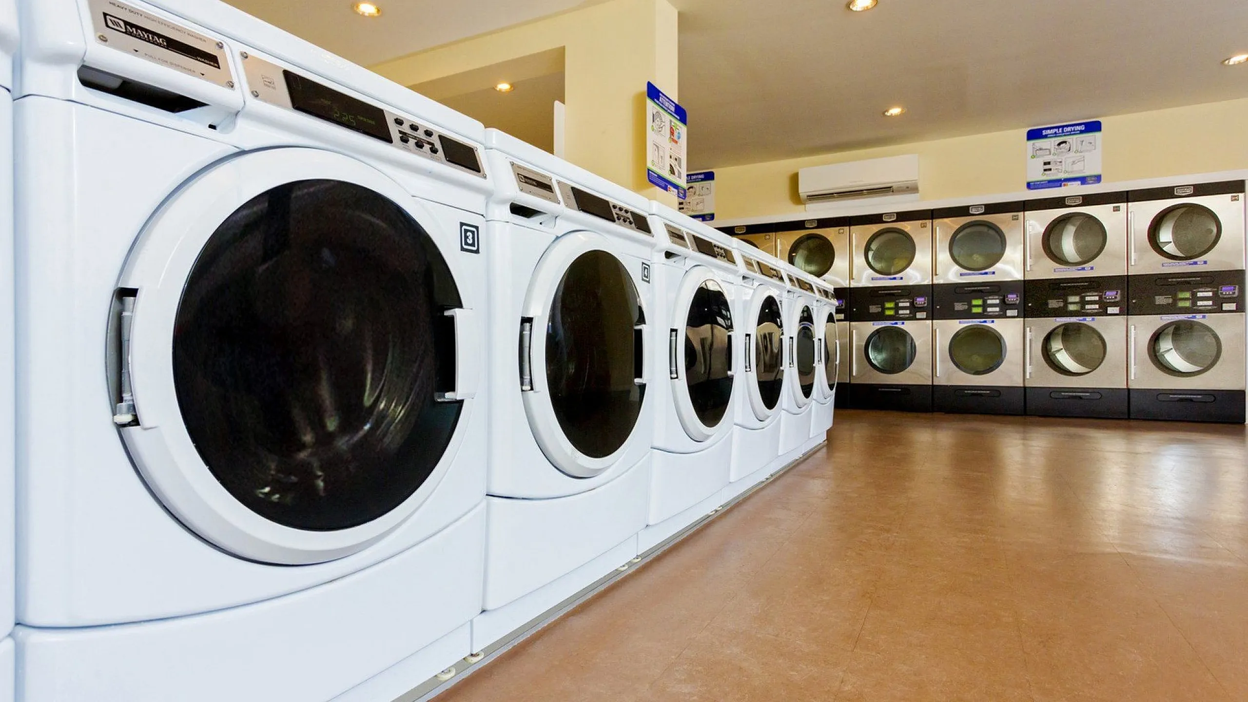 Bright and spacious laundry room featuring modern washing machines and dryers lined up for convenient use.