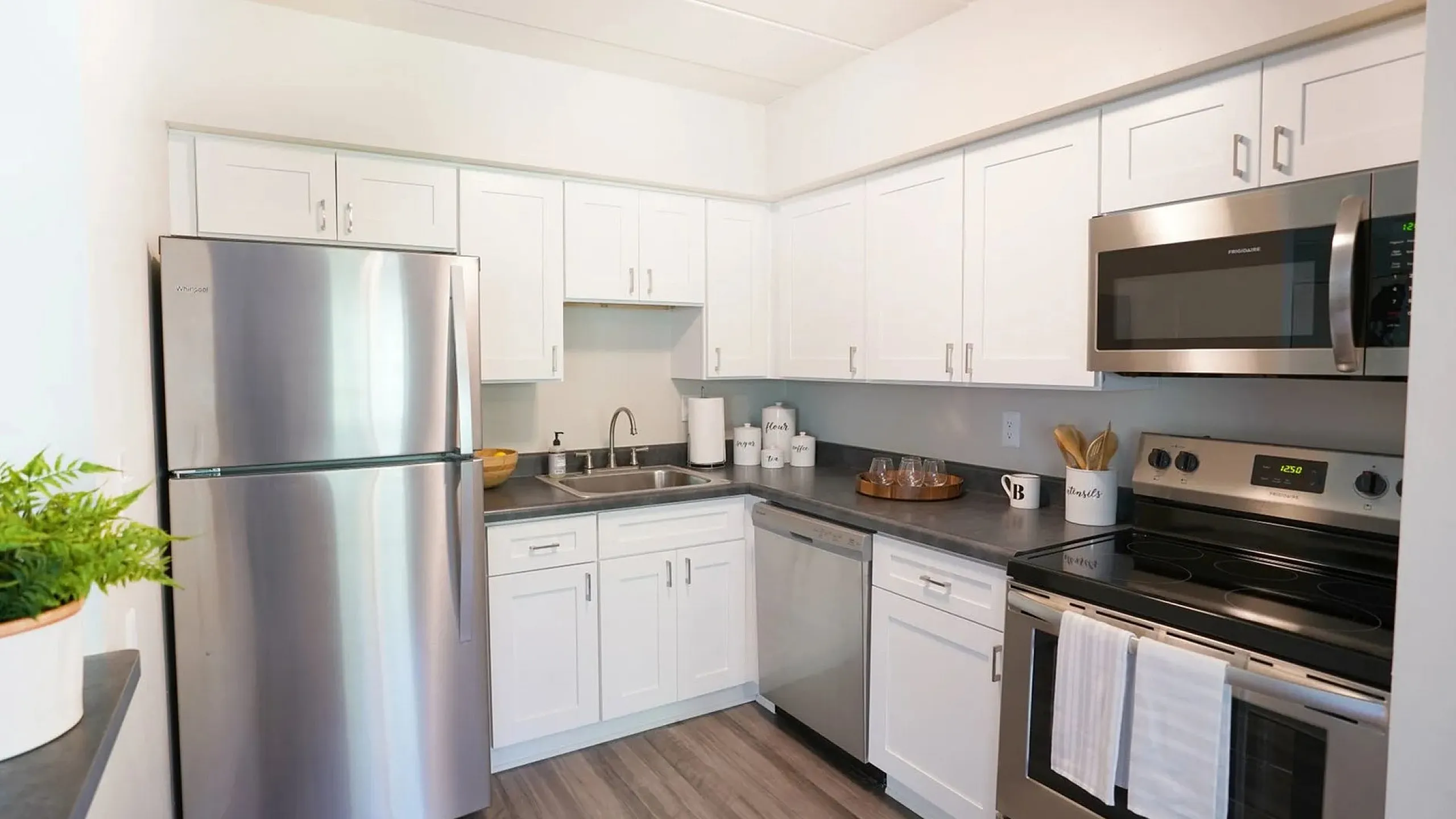 Modern kitchen with sleek stainless steel appliances, white cabinetry, and stylish laminate flooring.