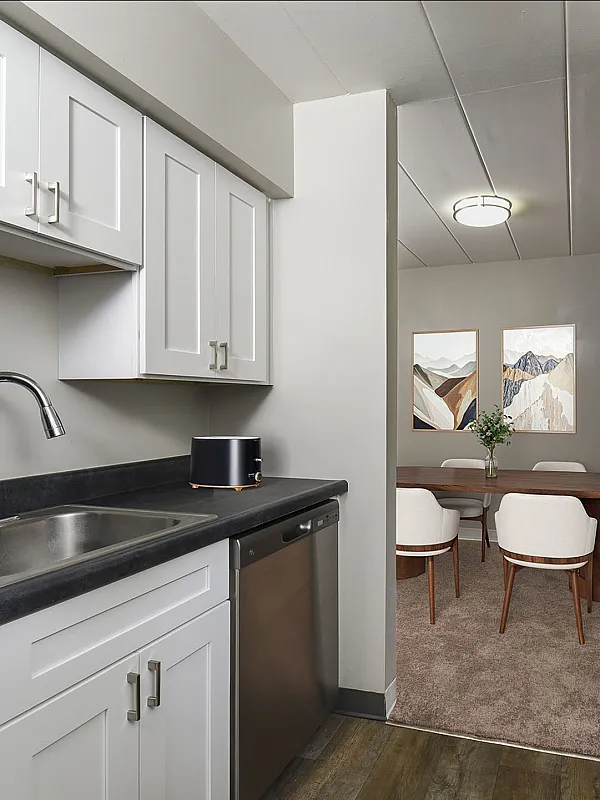 Modern kitchen with sleek appliances and elegant dining area, featuring contemporary artwork and cozy seating.