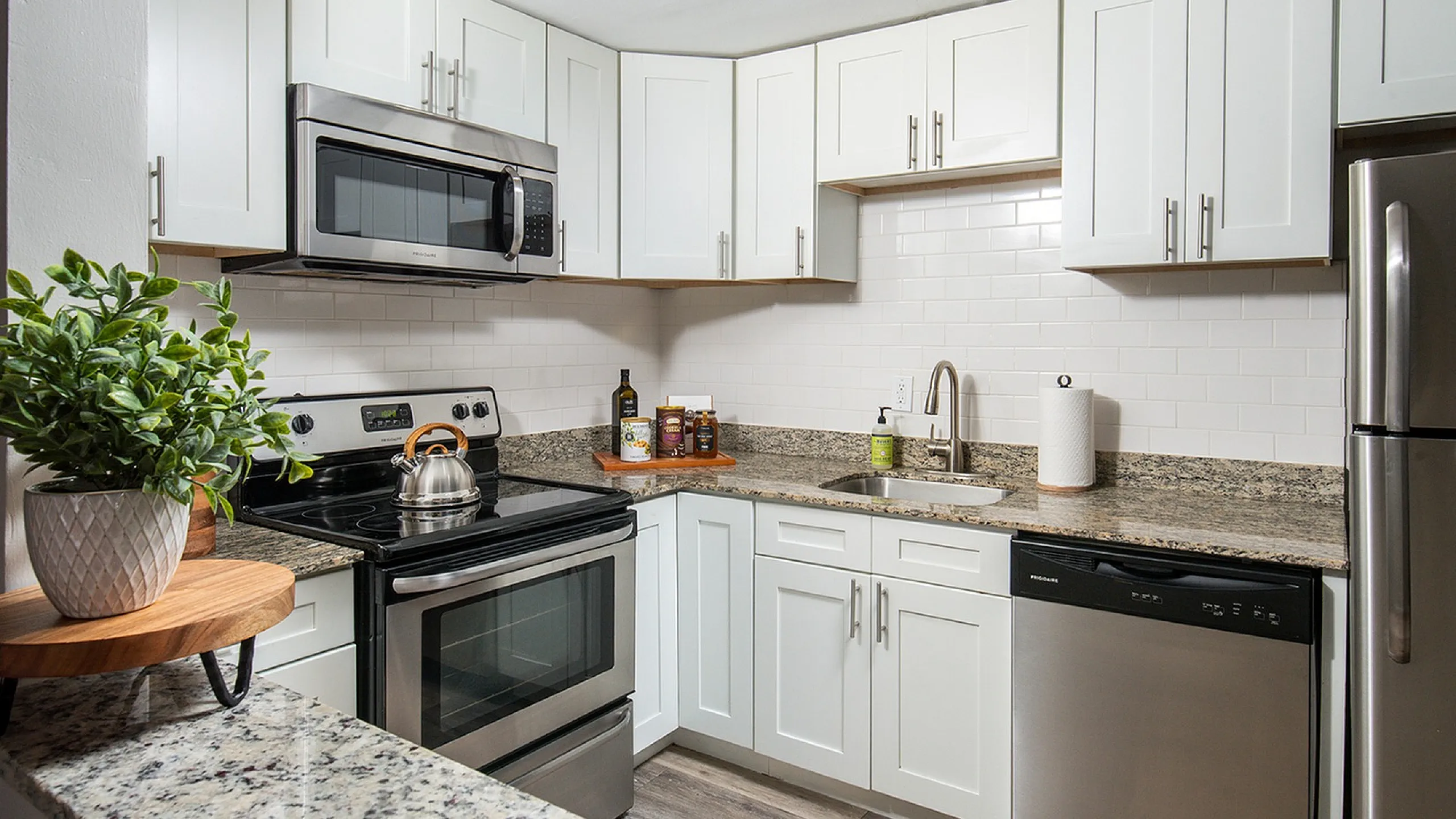 Modern kitchen with sleek stainless steel appliances, elegant granite countertops, and stylish white cabinetry offering ample storage.