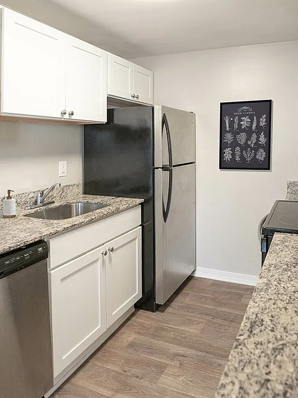 Modern kitchen with sleek granite countertops, white cabinetry, and stainless steel appliances, offering a stylish and functional cooking space.