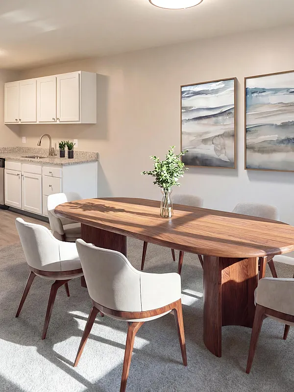 Sunlit open-concept dining area with modern kitchen, featuring elegant wooden table, plush chairs, and contemporary art decor.