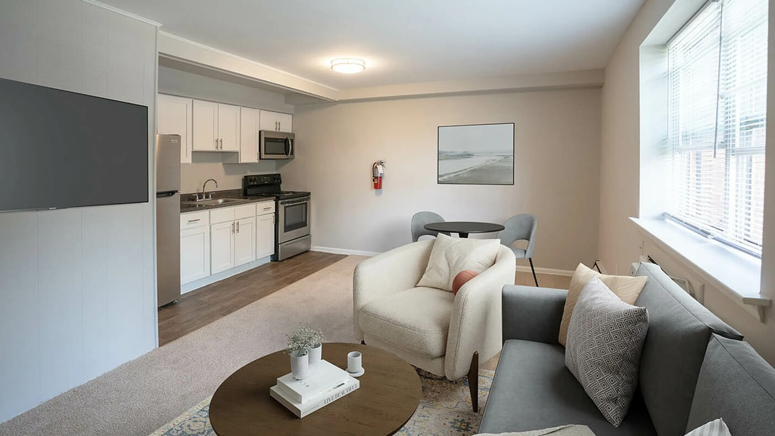 Bright and welcoming open-plan living area with modern kitchen, cozy seating, and large windows providing abundant natural light.