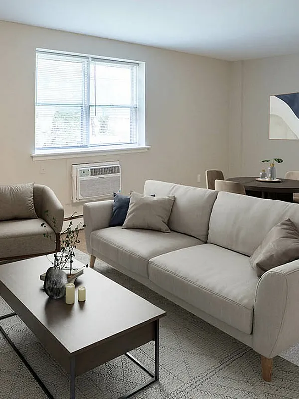 Elegant living room with a cozy beige sofa, modern armchair, stylish coffee table, and chic wall art, bathed in natural light from a large window.