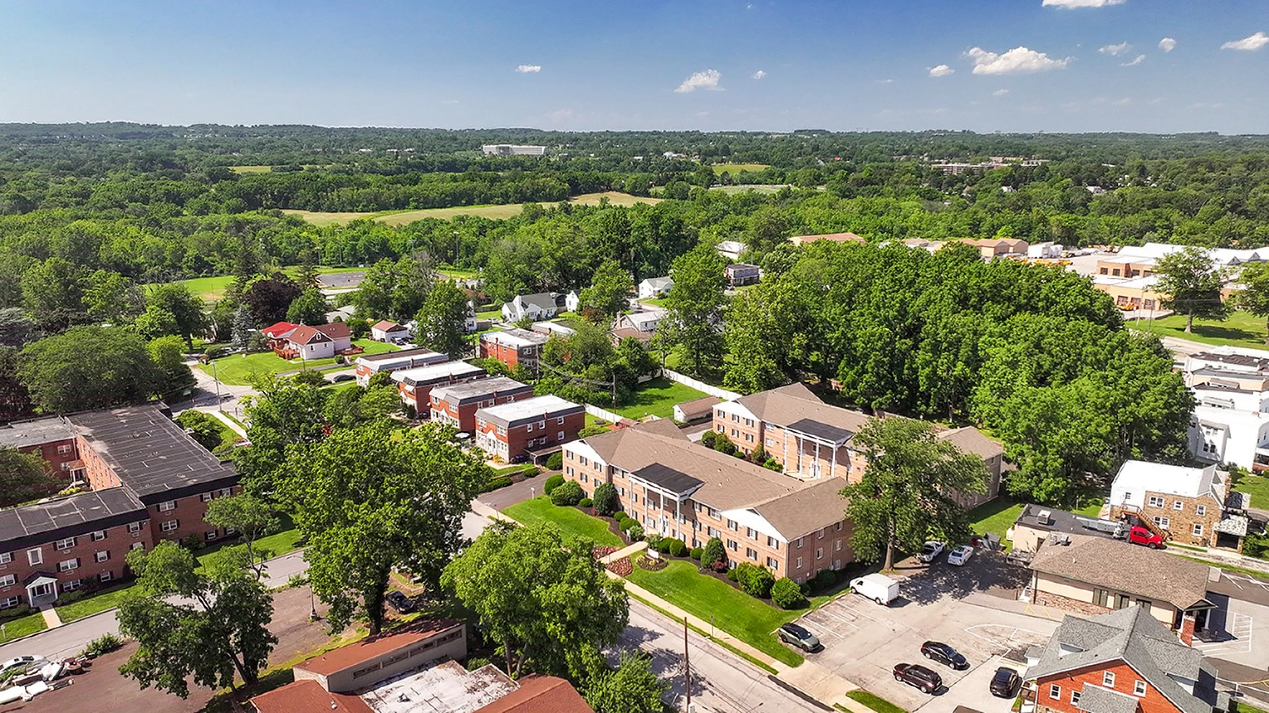 Charming aerial view of a lush suburban neighborhood with brick apartment buildings nestled among vibrant greenery.