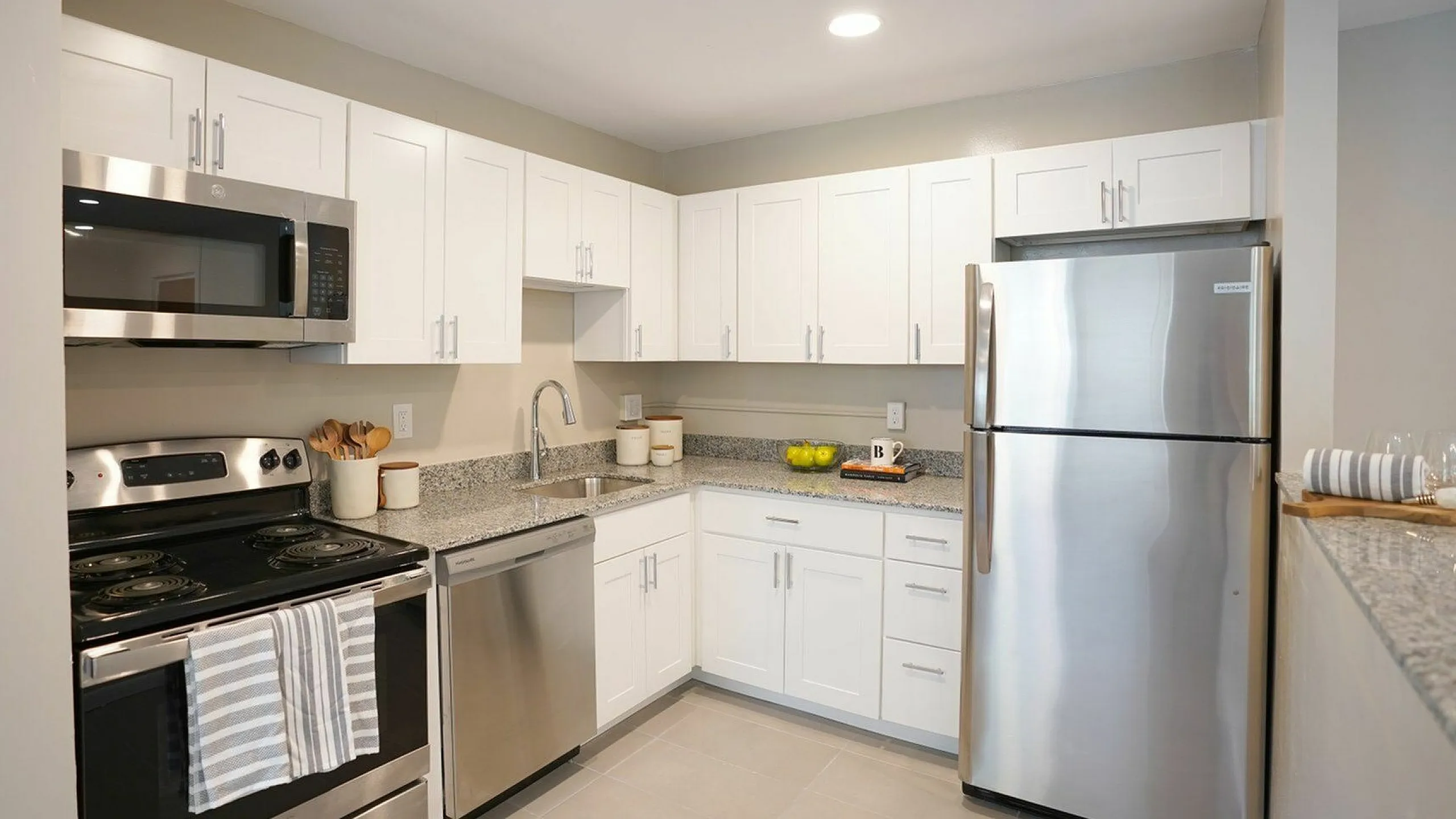Modern kitchen with sleek stainless steel appliances, granite countertops, and elegant white cabinetry, creating a stylish and functional culinary space.
