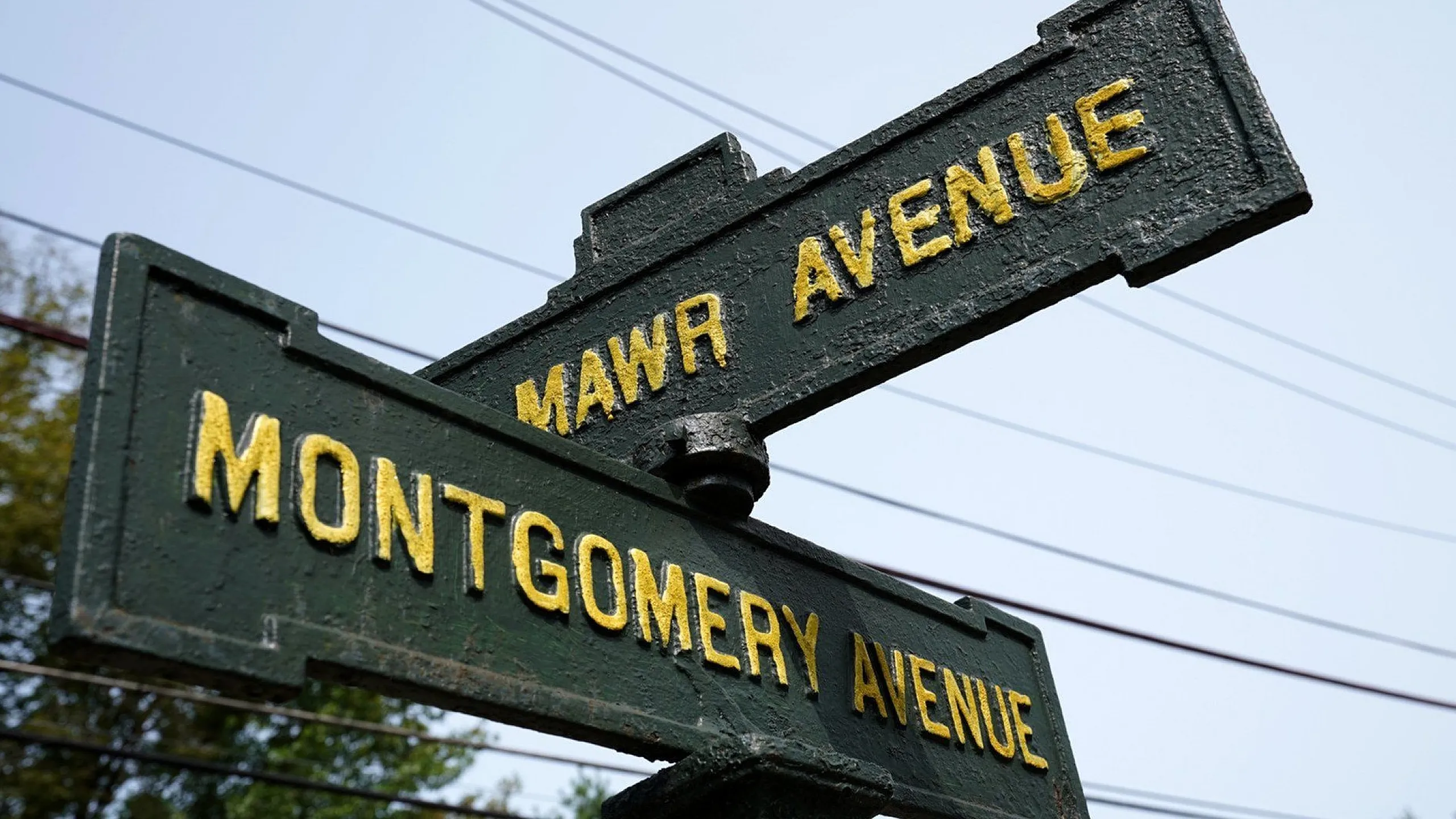 Charming vintage street signs at the intersection of Mawr Avenue and Montgomery Avenue, surrounded by lush greenery and blue skies.