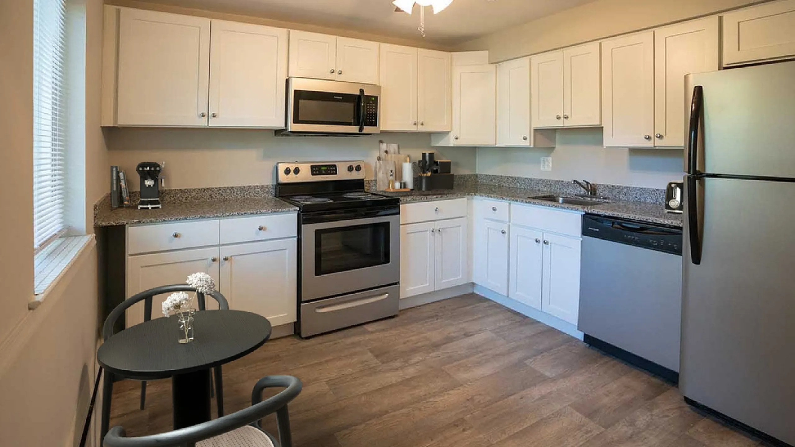 Modern kitchen with sleek stainless steel appliances, elegant white cabinetry, and a cozy dining nook with natural light.