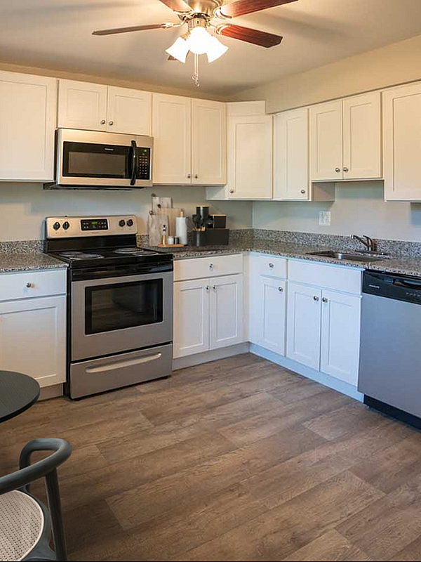 Modern kitchen with stainless steel appliances, elegant white cabinets, and a cozy dining nook with stylish furniture.