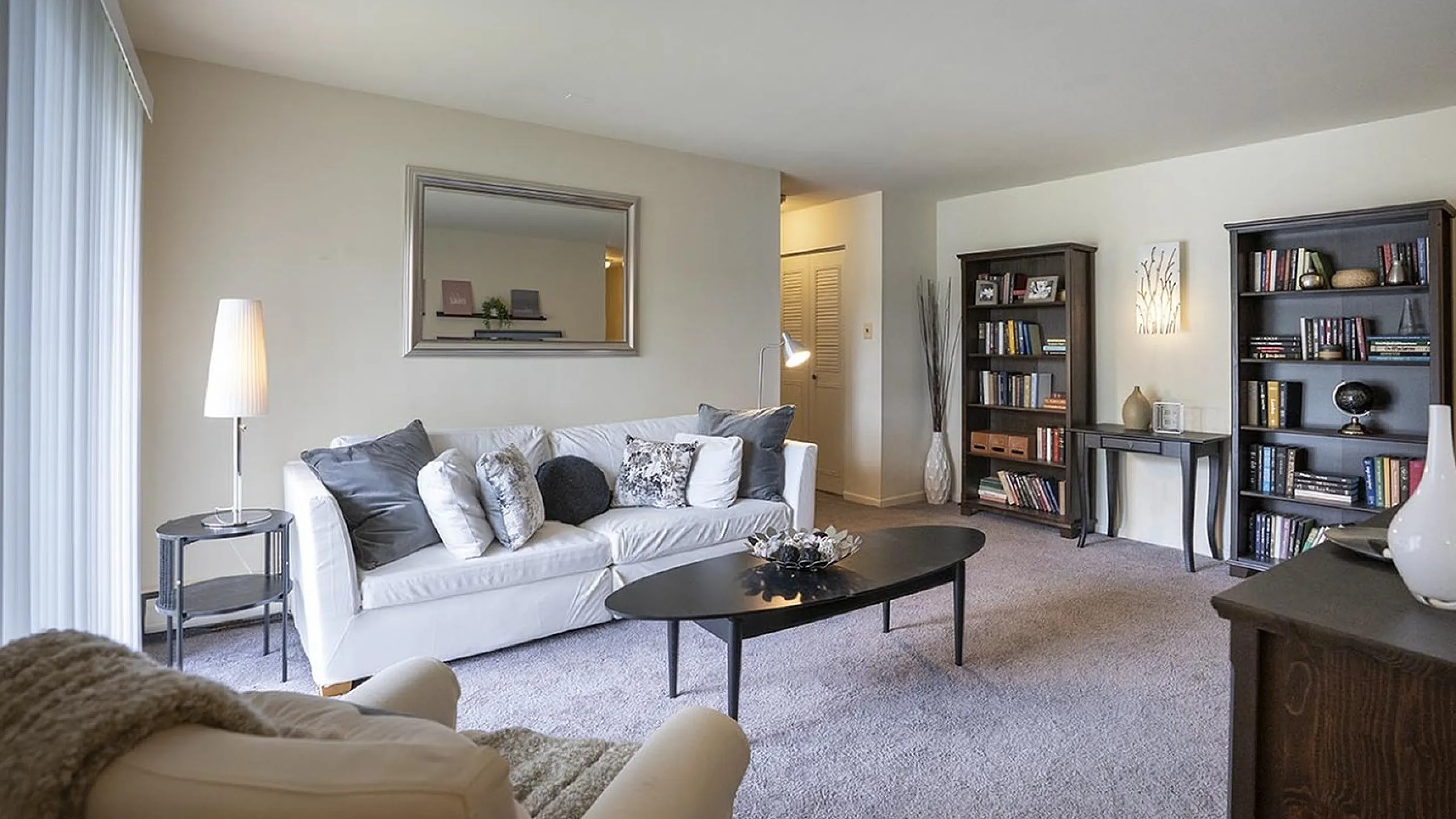 Inviting living room featuring a cozy white sofa, elegant black coffee table, and stylish bookcases for a warm, sophisticated ambiance.