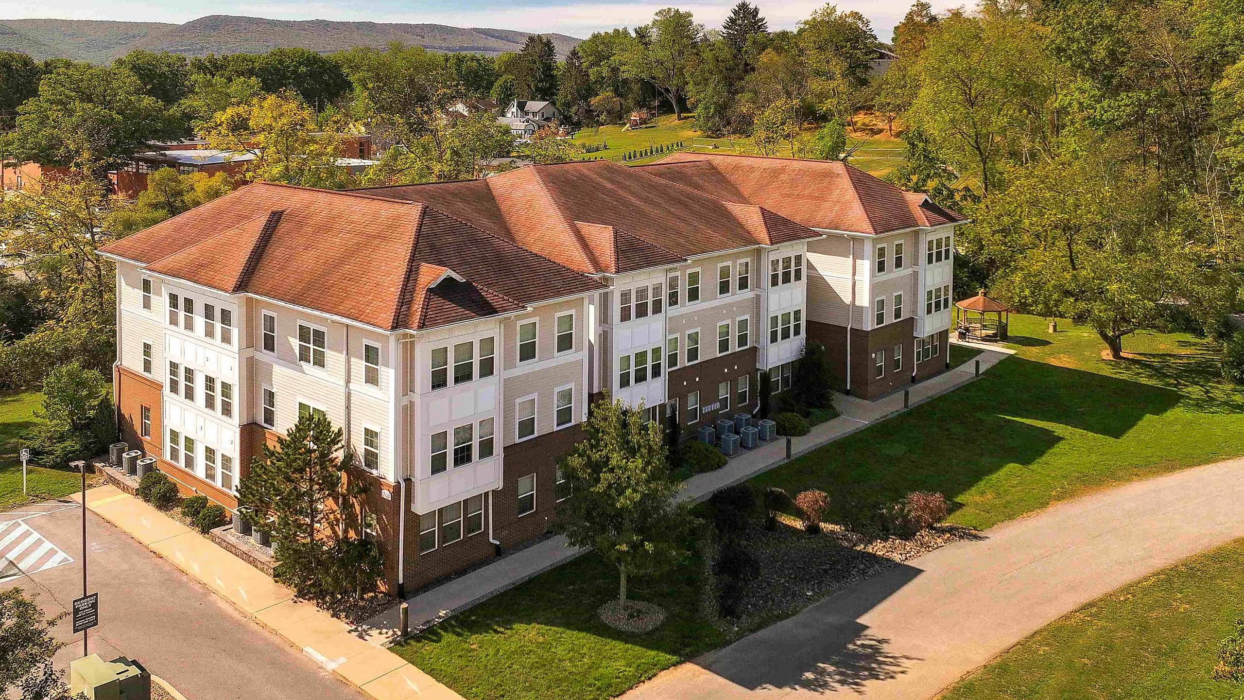 Charming apartment building surrounded by lush greenery and scenic mountain views, offering a peaceful suburban lifestyle.