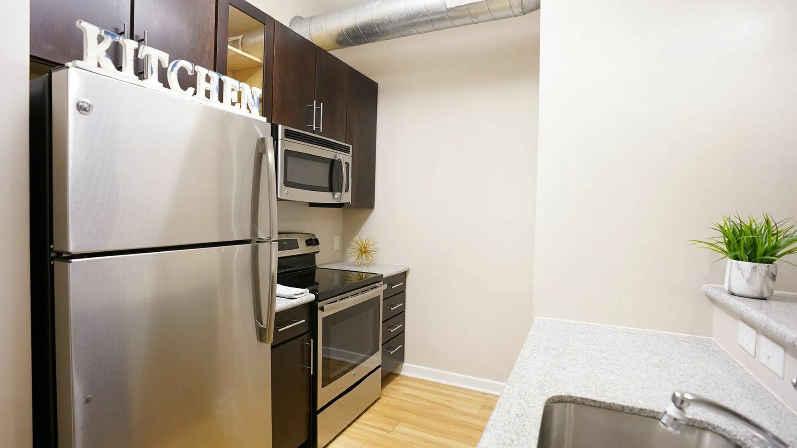 Modern kitchen with sleek stainless steel appliances, dark wood cabinets, and elegant countertops, enhancing an inviting cooking space.