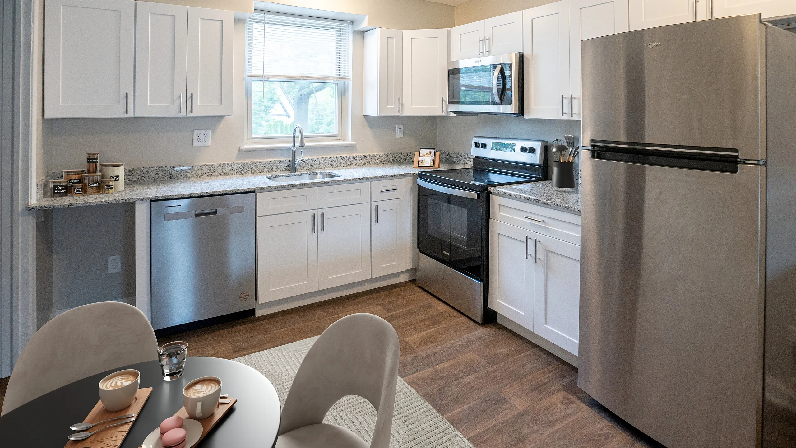 Modern kitchen with sleek stainless steel appliances, elegant white cabinetry, and a cozy breakfast nook featuring cappuccinos and macarons.