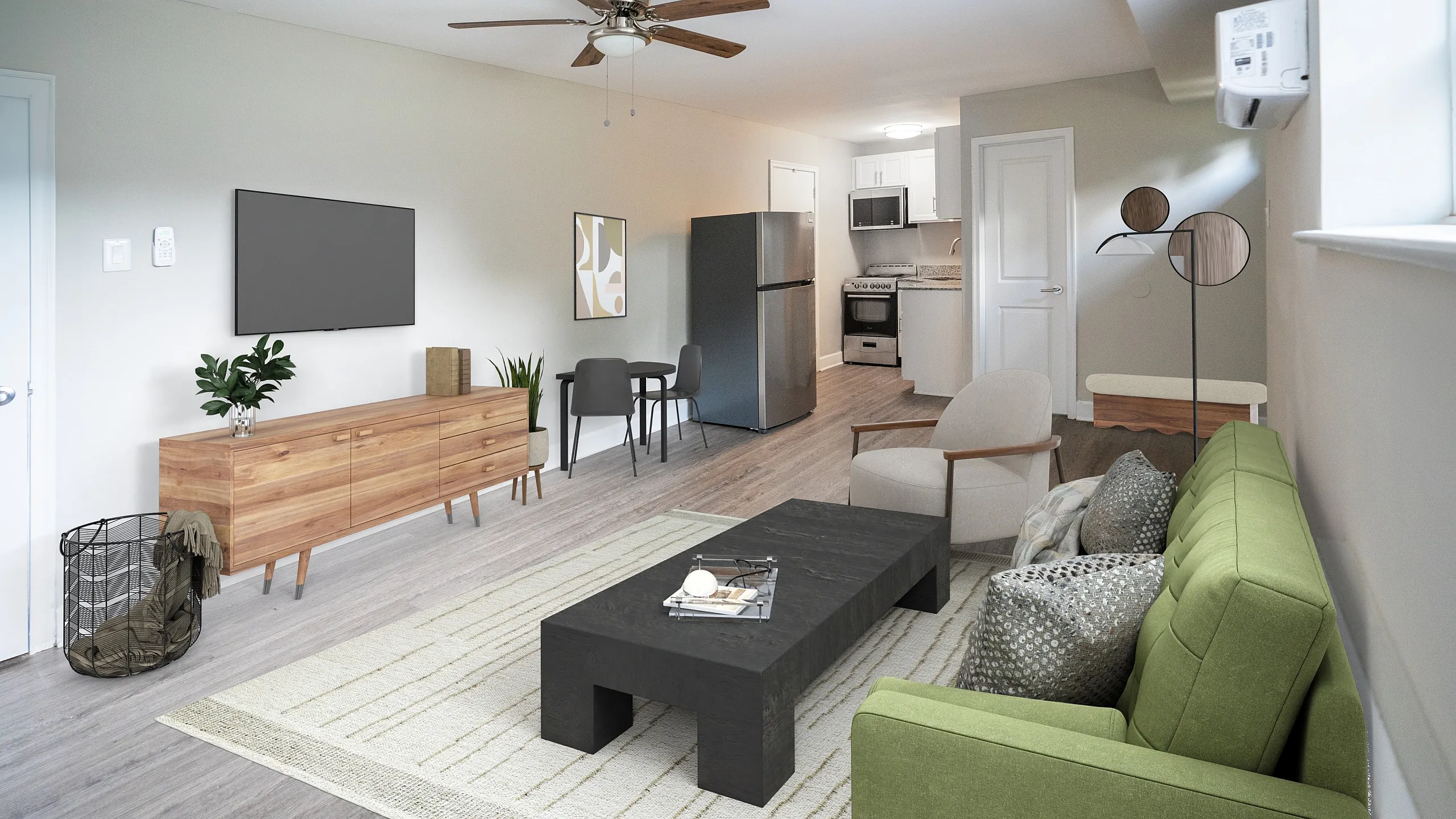 Modern open-layout apartment with a cozy green sofa, sleek black coffee table, and a contemporary kitchen. Warm wood tones enhance inviting atmosphere.