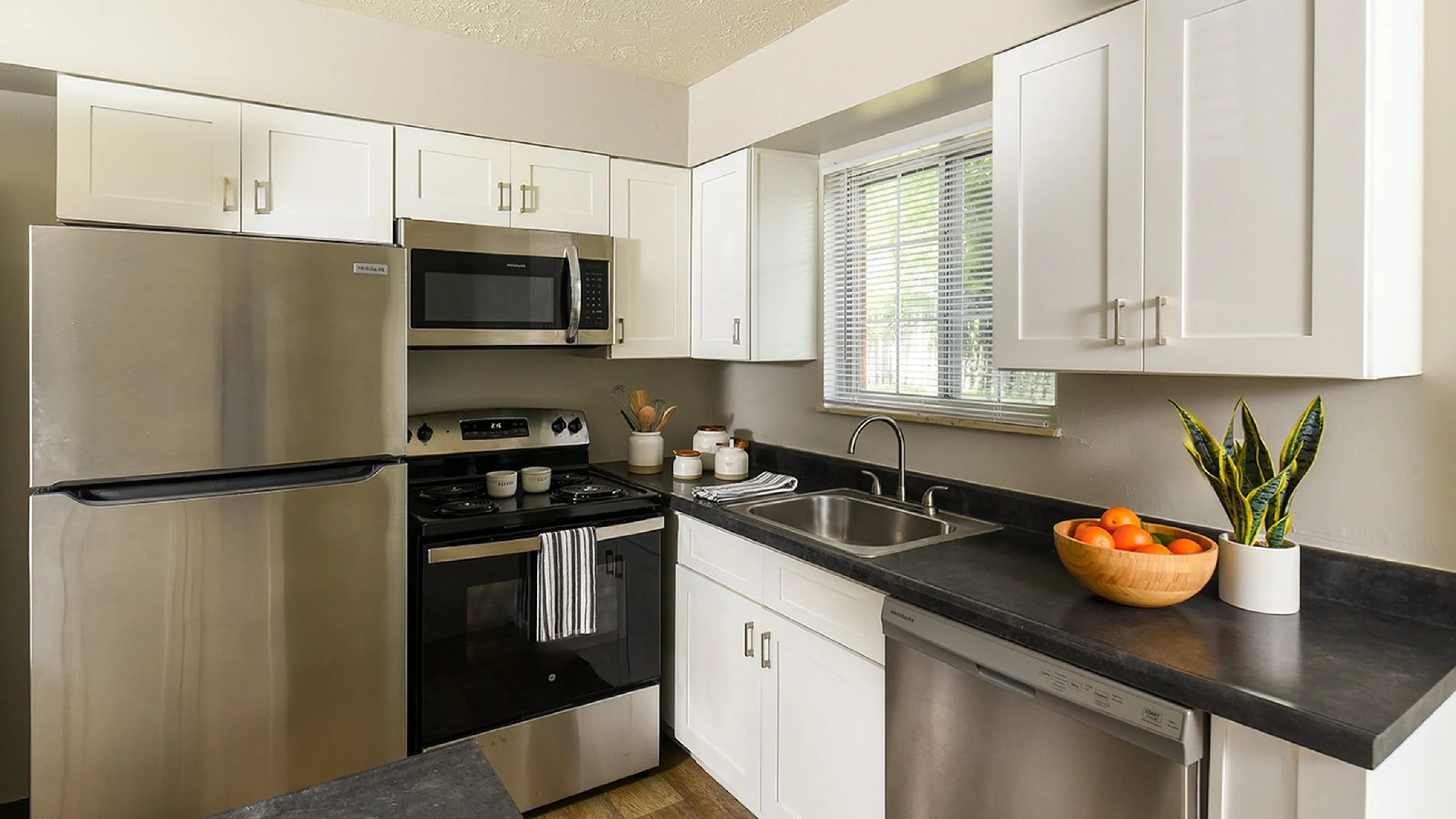 Modern kitchen with stainless steel appliances, elegant white cabinets, and a sunlit window for natural brightness.