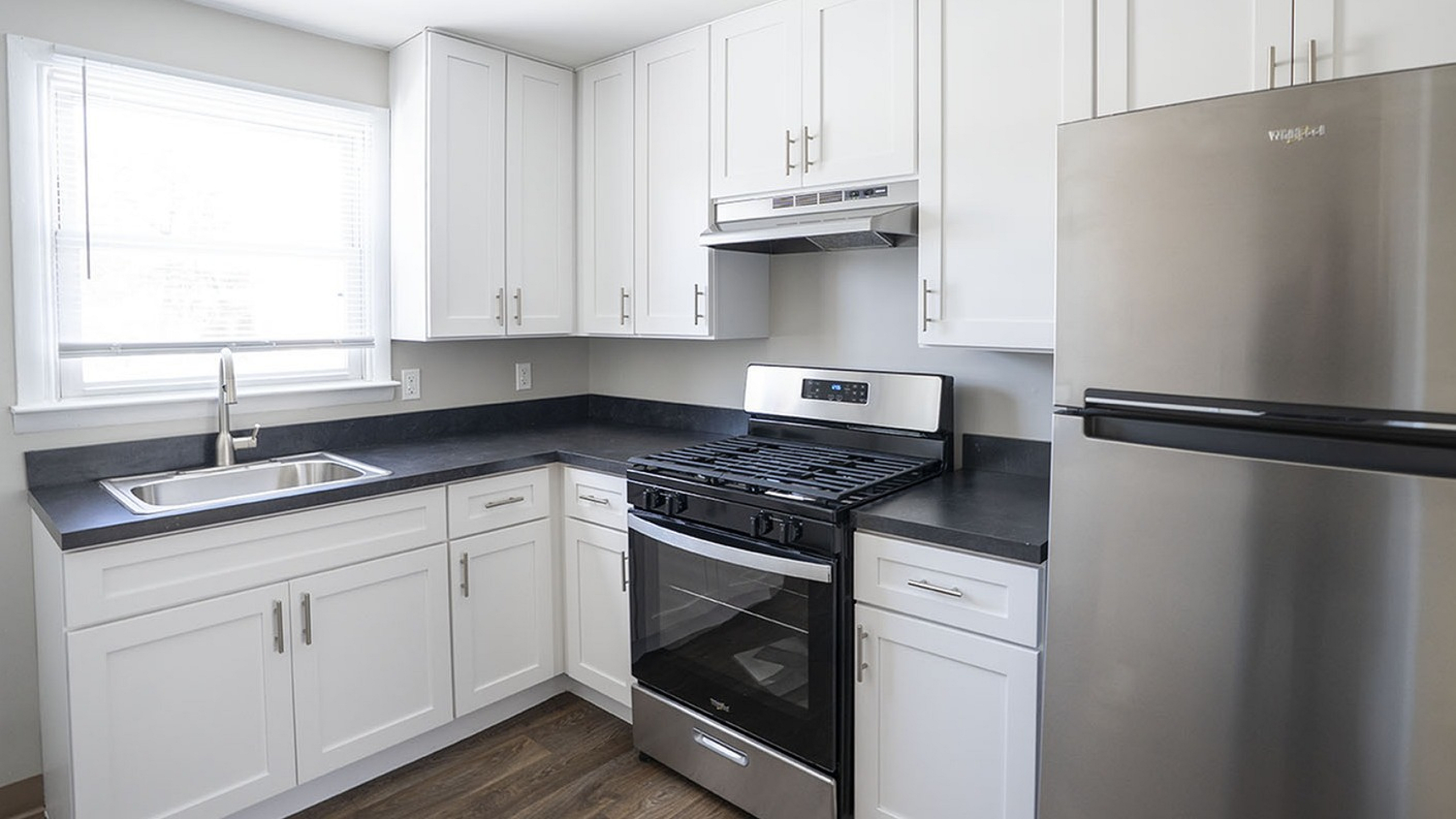 Modern kitchen with sleek stainless steel appliances, white cabinetry, and elegant dark countertops.