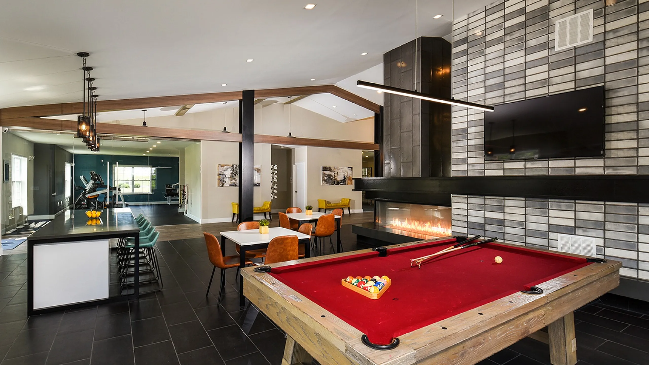 Chic modern apartment lounge featuring a stylish billiards table, cozy fireplace, and vibrant seating area with contemporary decor.