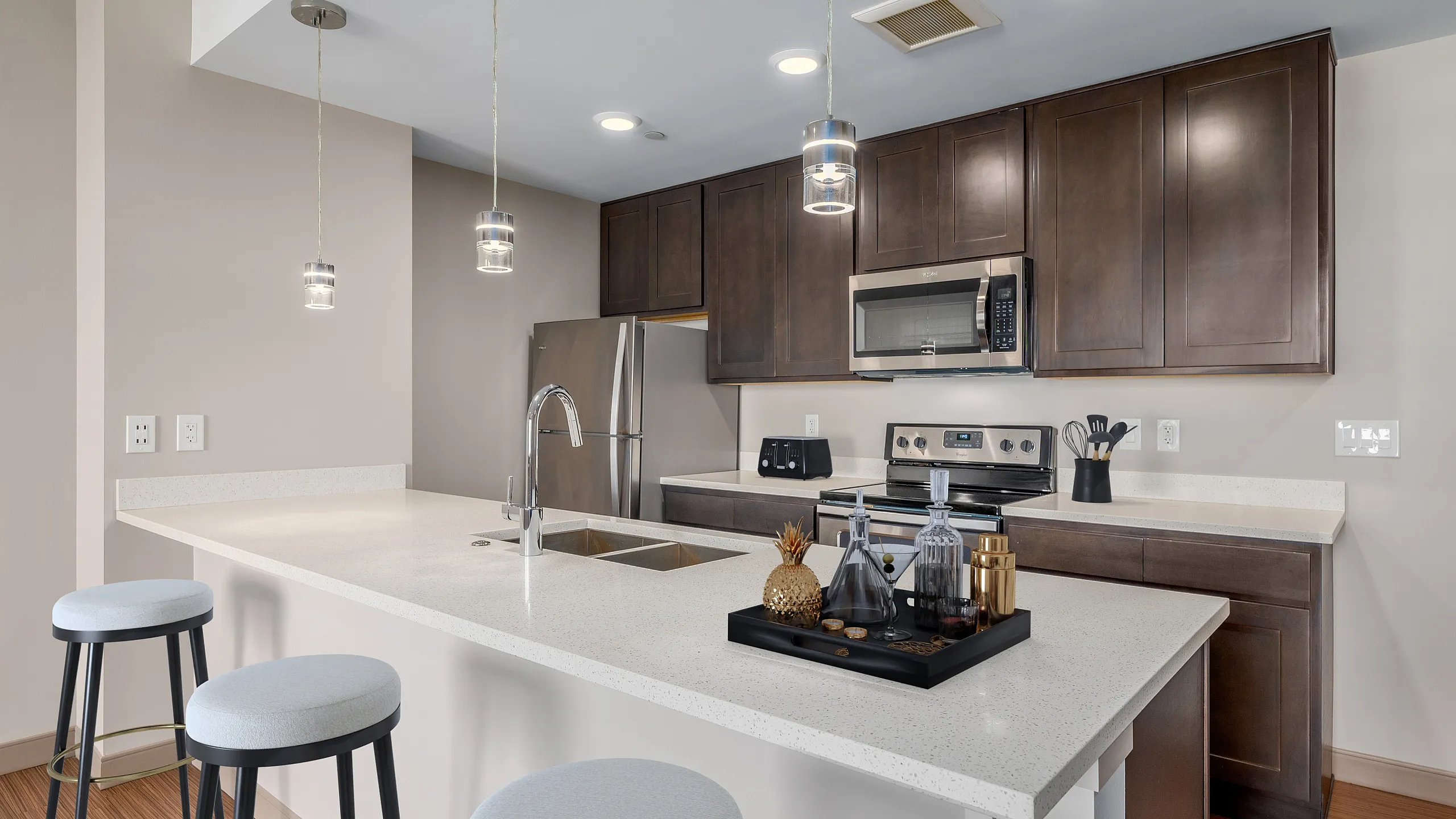 Modern kitchen with sleek stainless steel appliances, elegant dark wood cabinets, and a spacious white quartz countertop island with stylish pendant lighting.