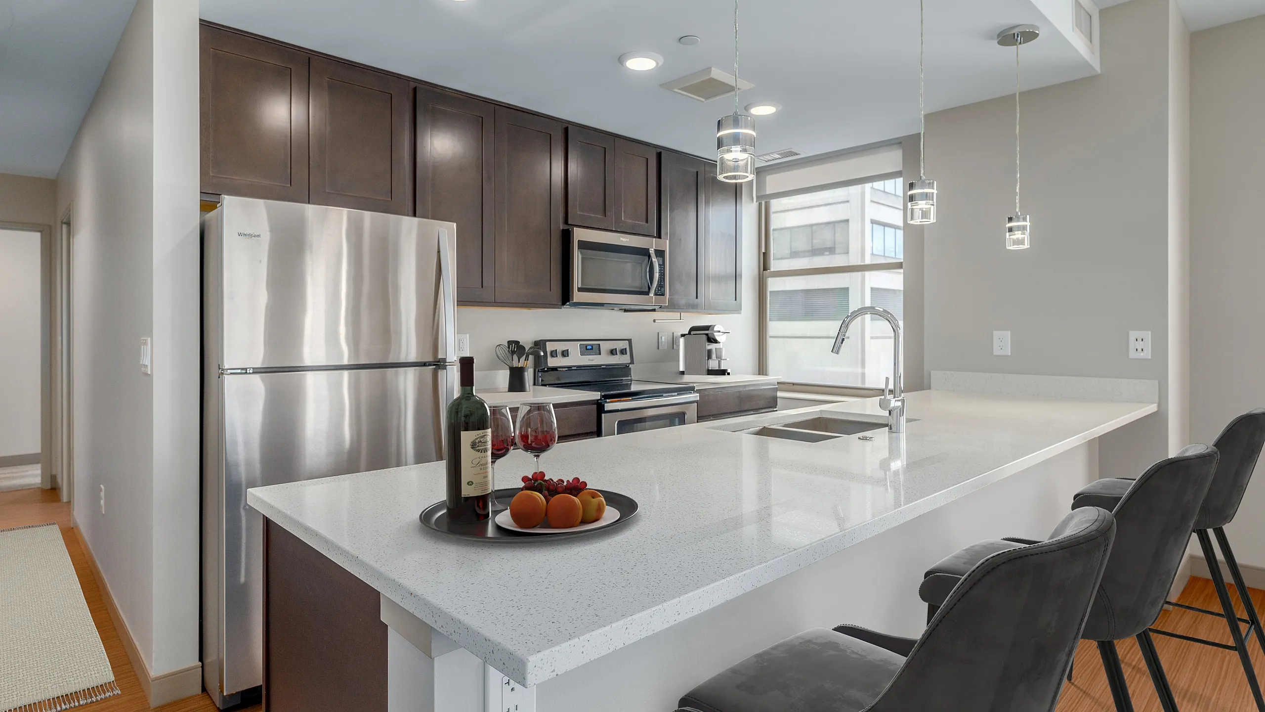 Modern kitchen with sleek stainless steel appliances, elegant dark wood cabinets, and a spacious quartz countertop island with stylish pendant lighting and cozy bar seating.