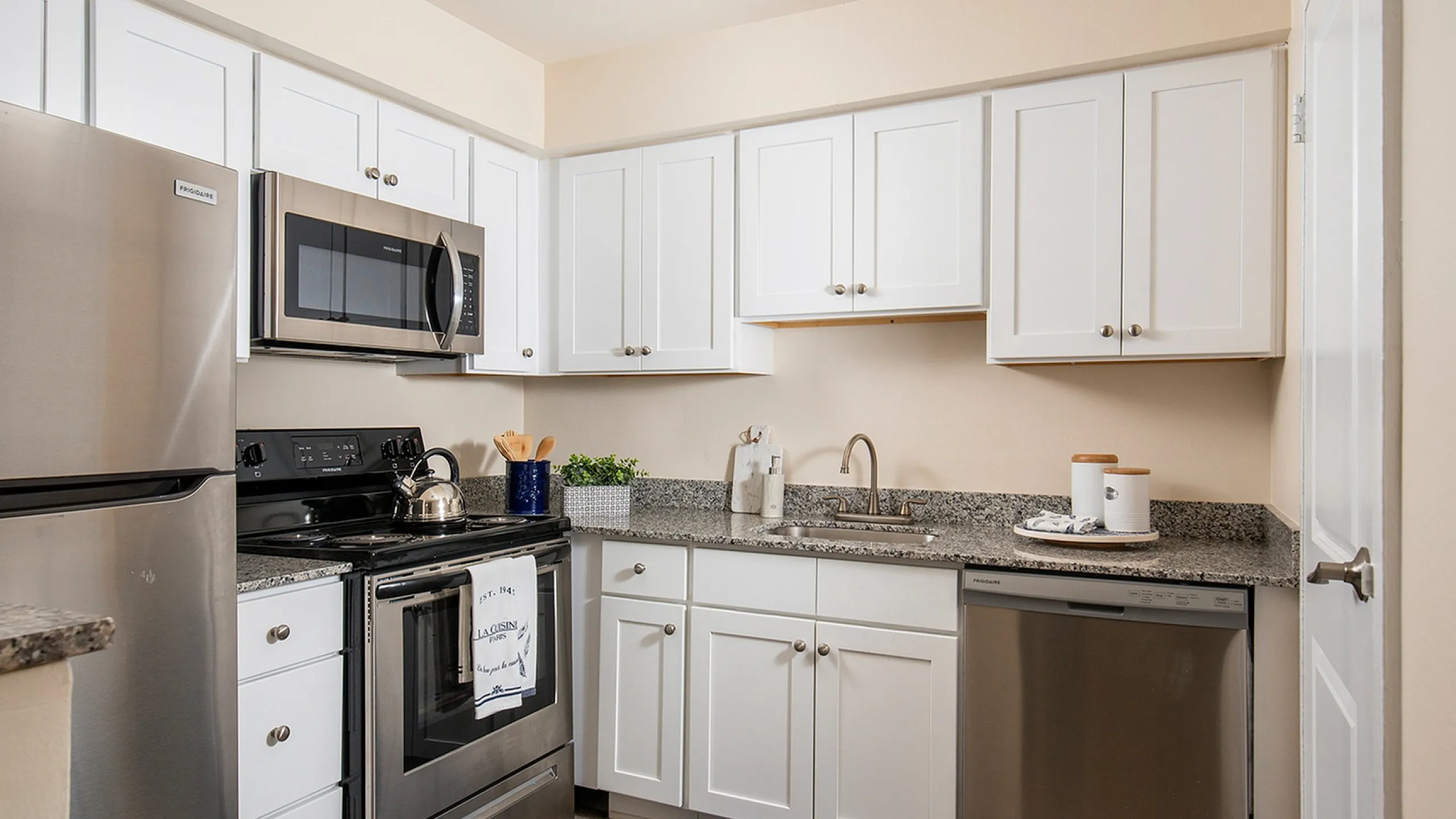 Modern kitchen with sleek stainless steel appliances, granite countertops, and elegant white cabinetry offering a bright and functional cooking space.