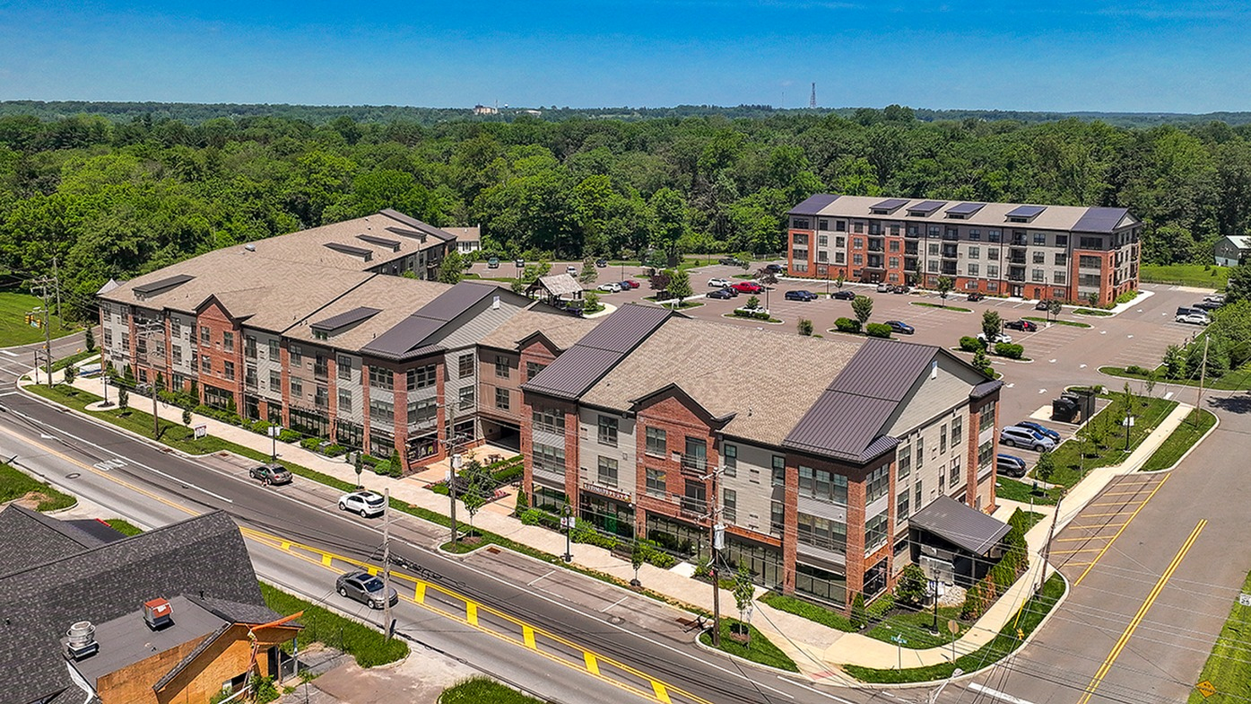 Modern apartment complex surrounded by lush greenery, featuring spacious parking and stylish architecture in a vibrant neighborhood.