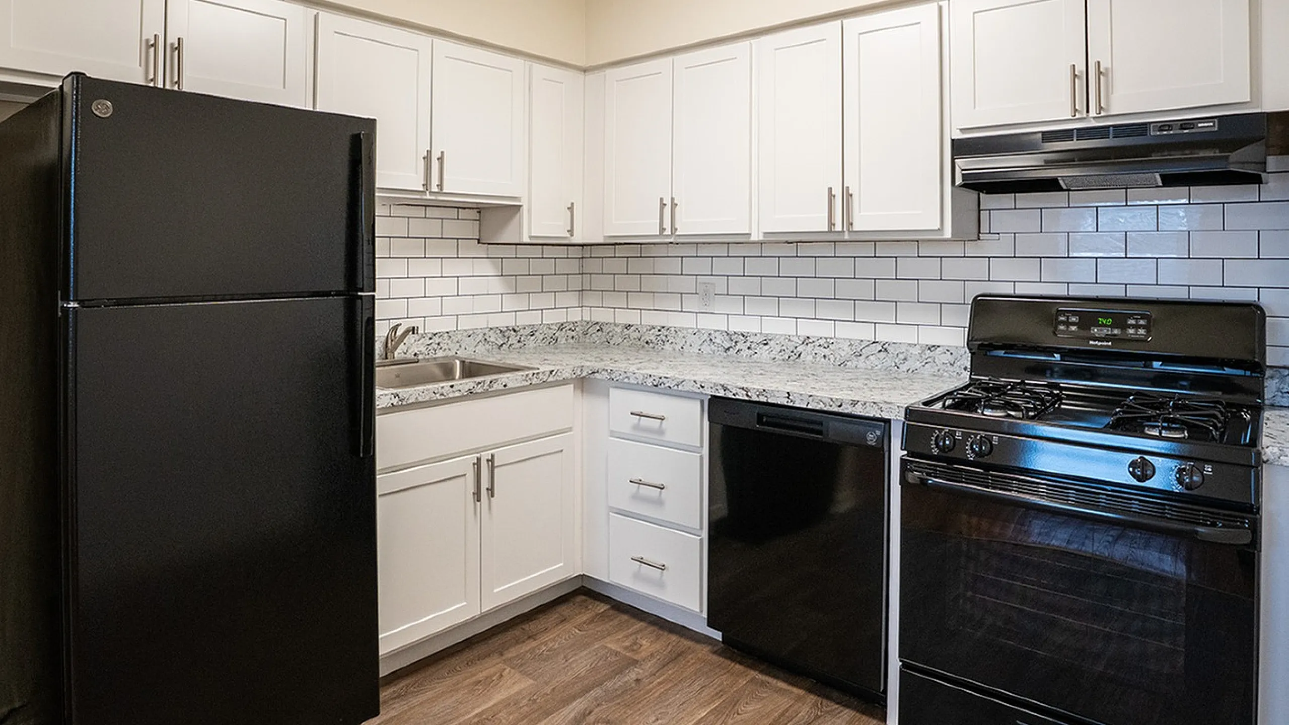 Modern kitchen featuring sleek black appliances, elegant white cabinetry, and stylish subway tile backsplash.