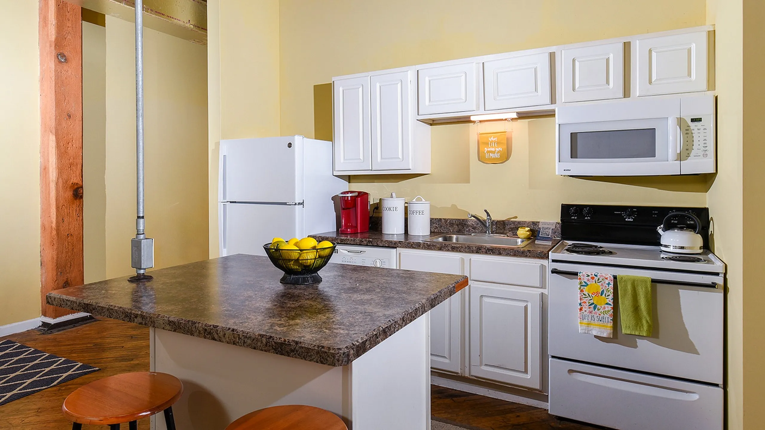 Charming kitchen features modern appliances, a stylish island with barstool seating, and a cozy, inviting atmosphere.