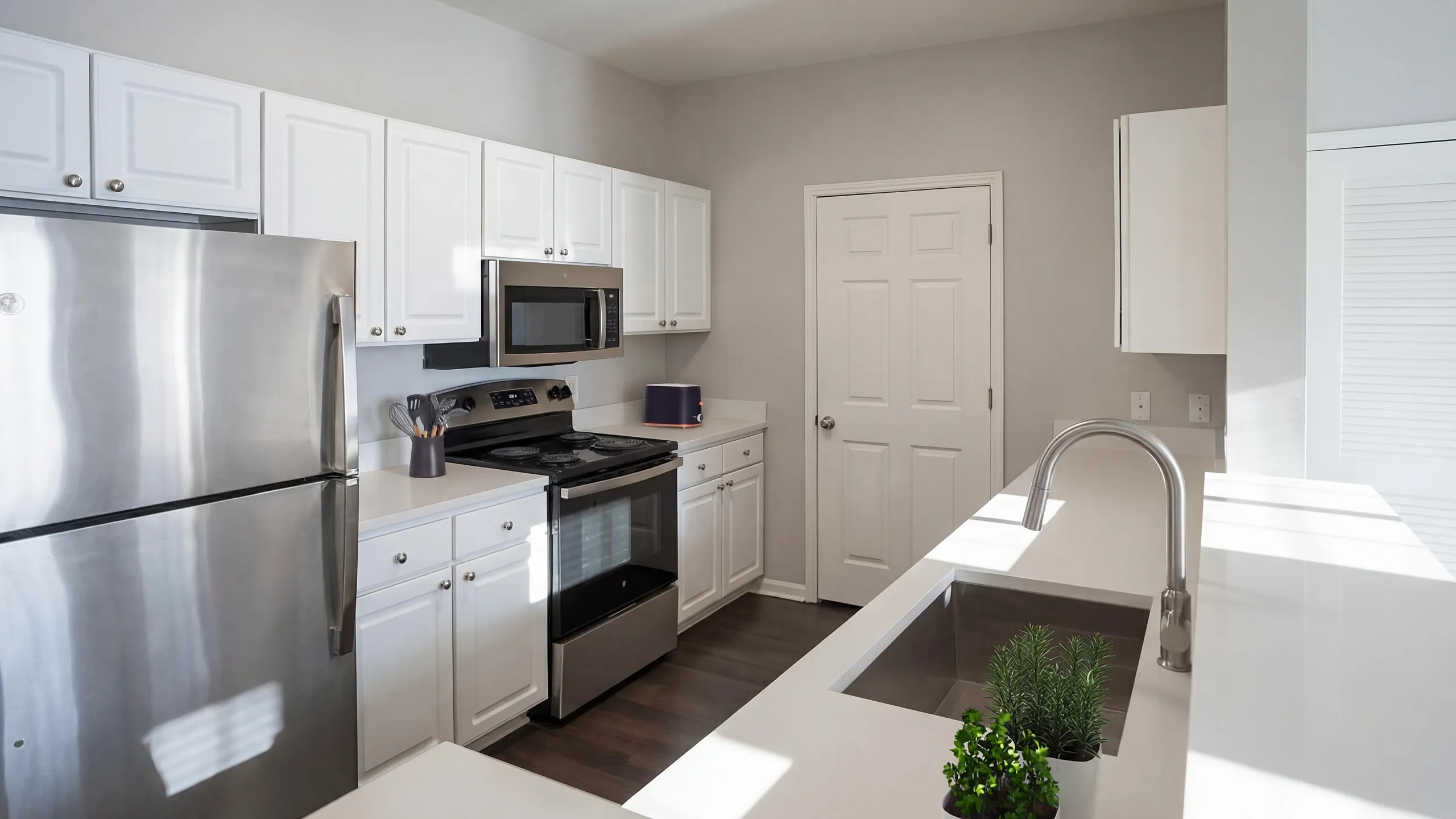 Modern kitchen with sleek stainless steel appliances, elegant white cabinetry, and a stylish sink island, filled with natural light.