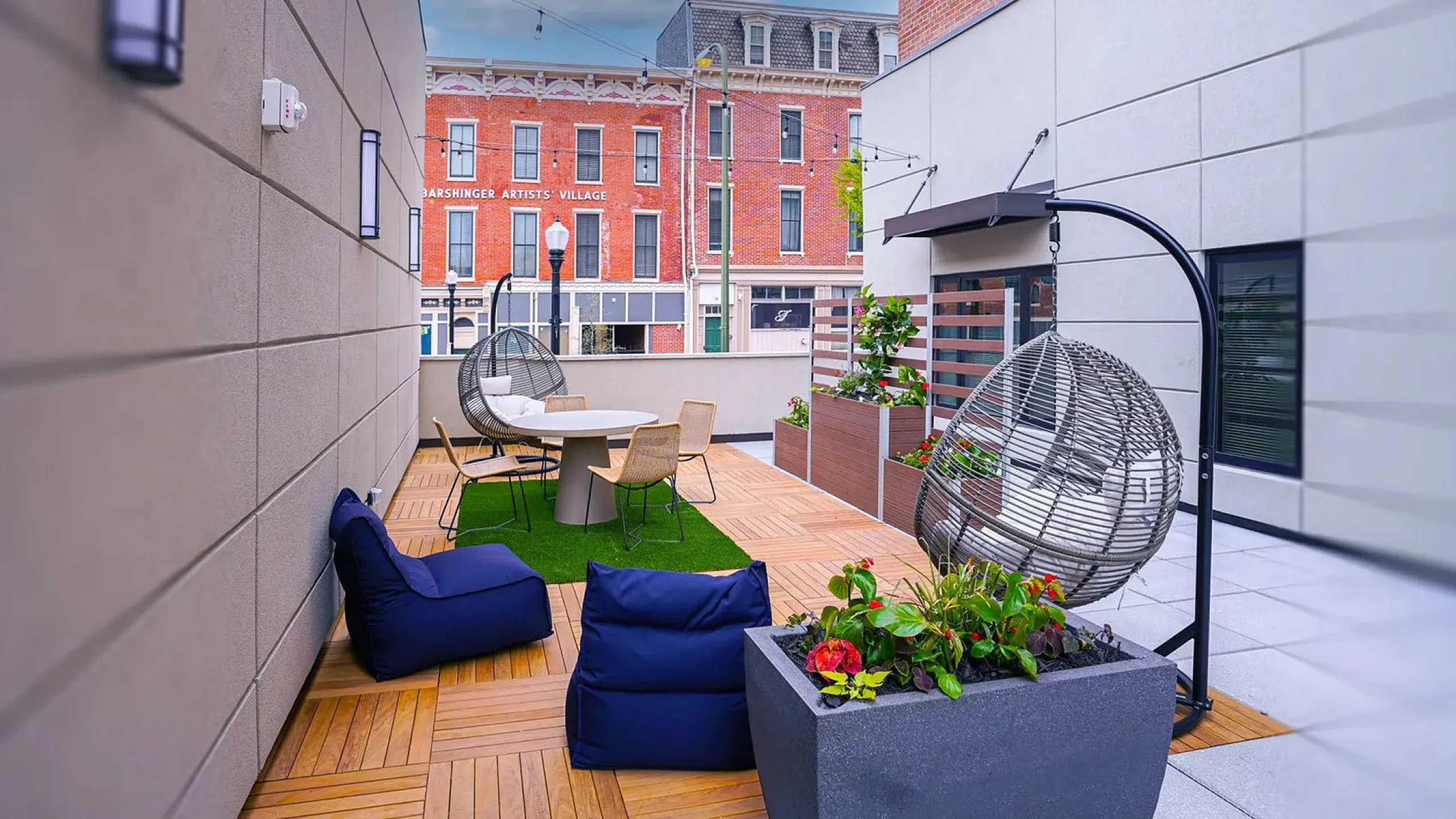 Charming urban terrace featuring modern seating, lush planters, and cozy lighting with a city view backdrop.