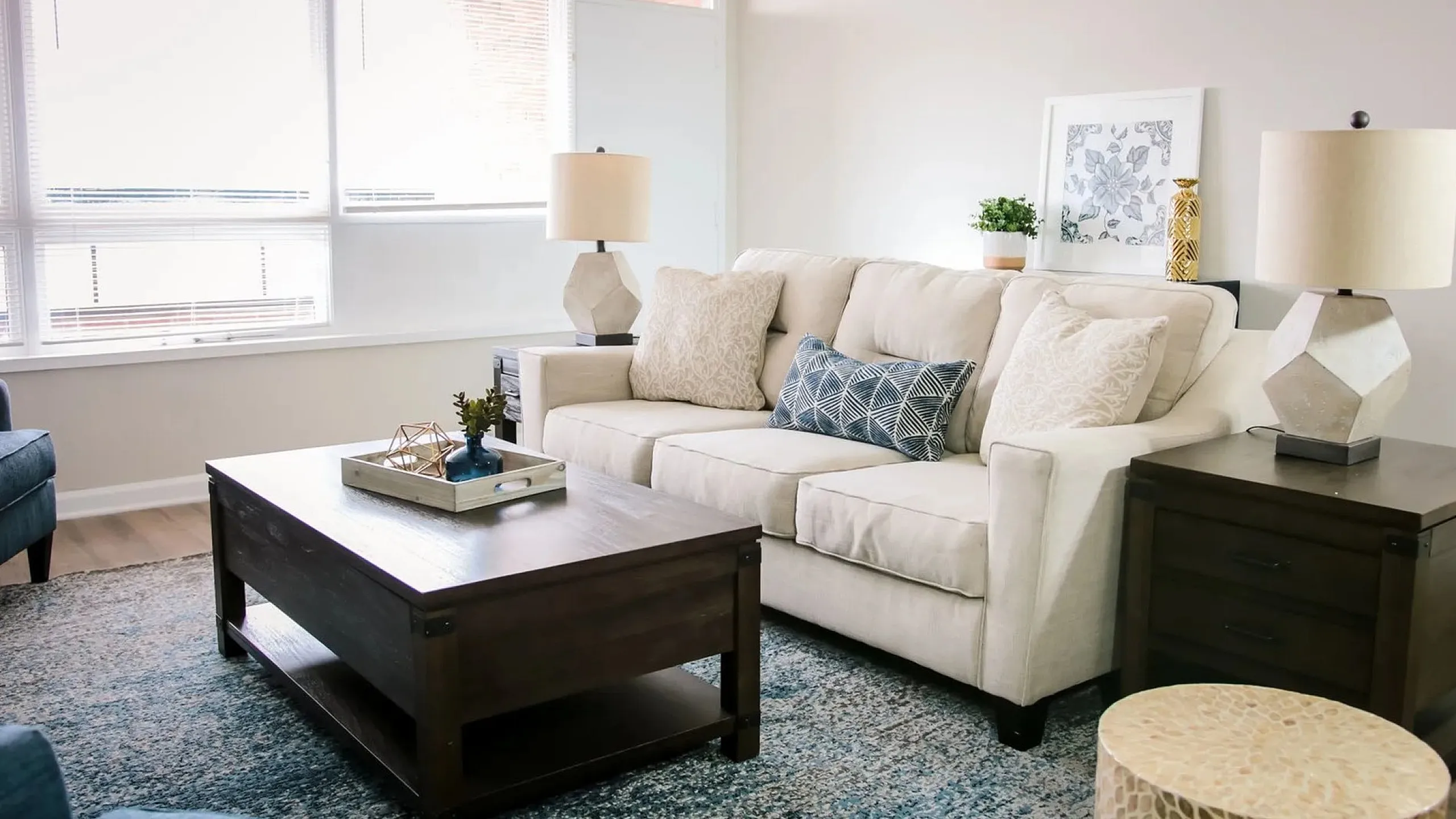 Bright and inviting living room featuring a plush beige sofa, modern geometric lamps, and a chic coffee table, complemented by a soothing blue and white color palette.