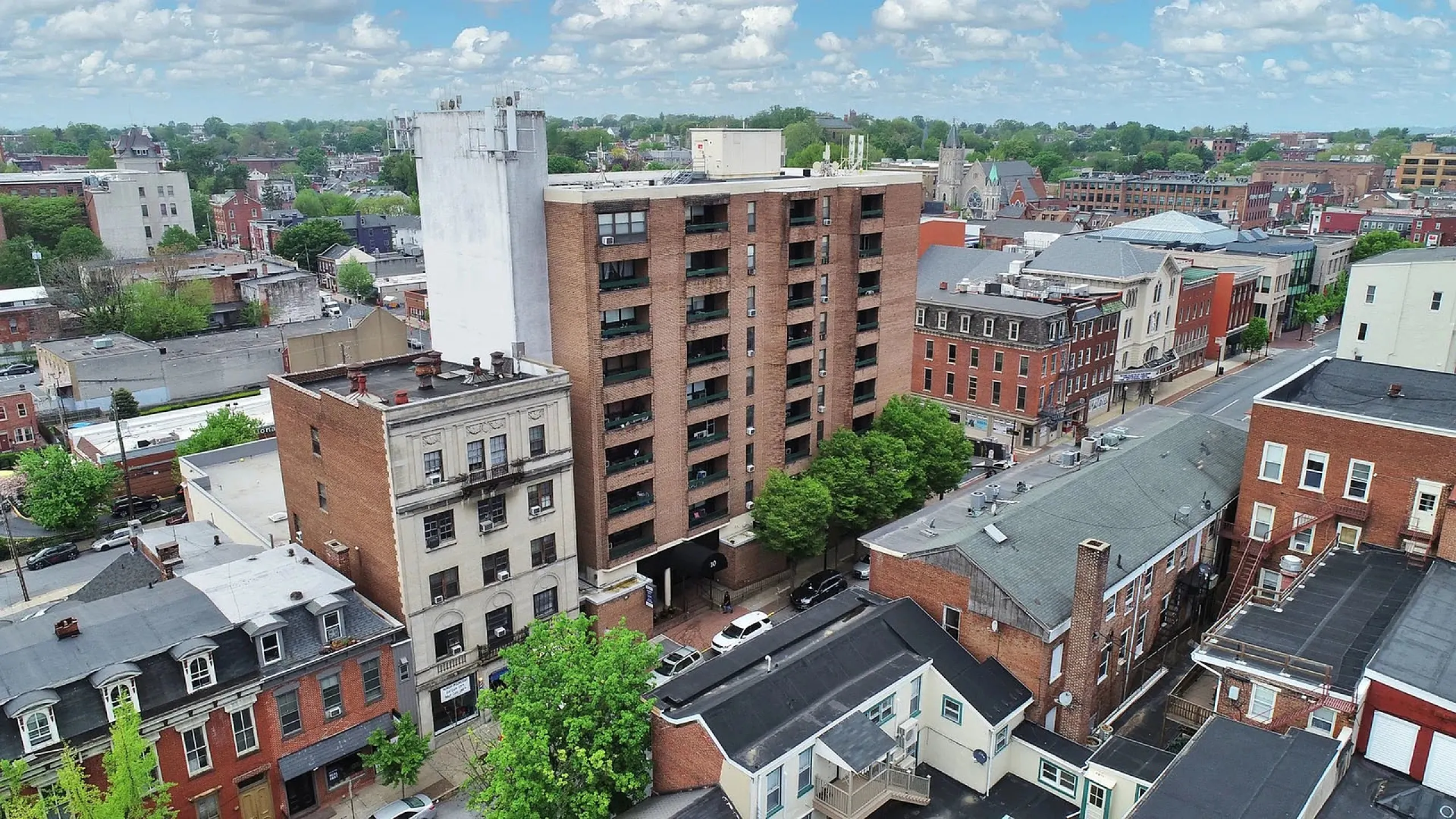 Charming urban residential building nestled in a vibrant cityscape, surrounded by lush greenery and historic architecture.