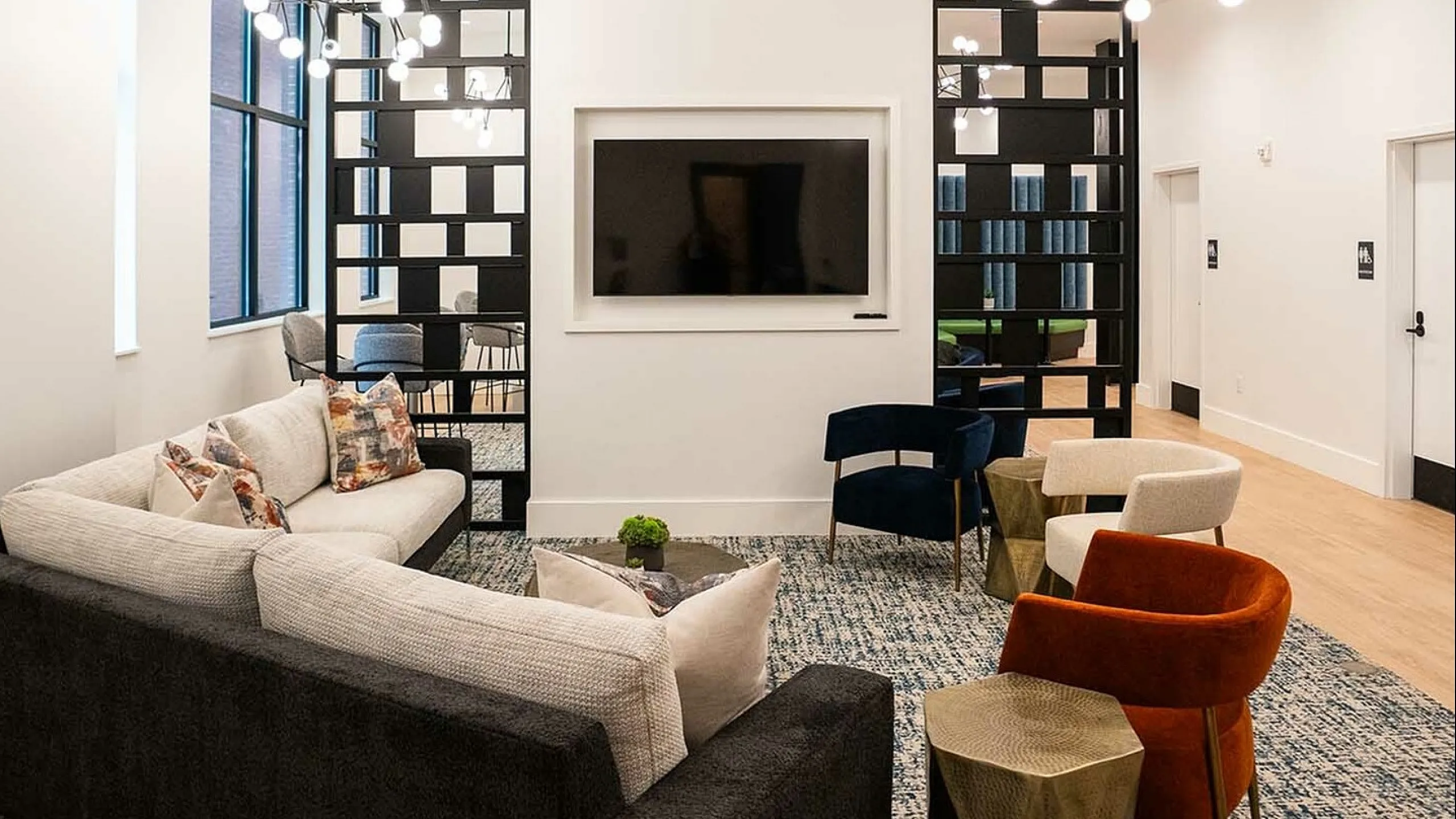 Elegant living area with modern design featuring chic furniture, a large flat-screen TV, and stylish lighting fixtures.