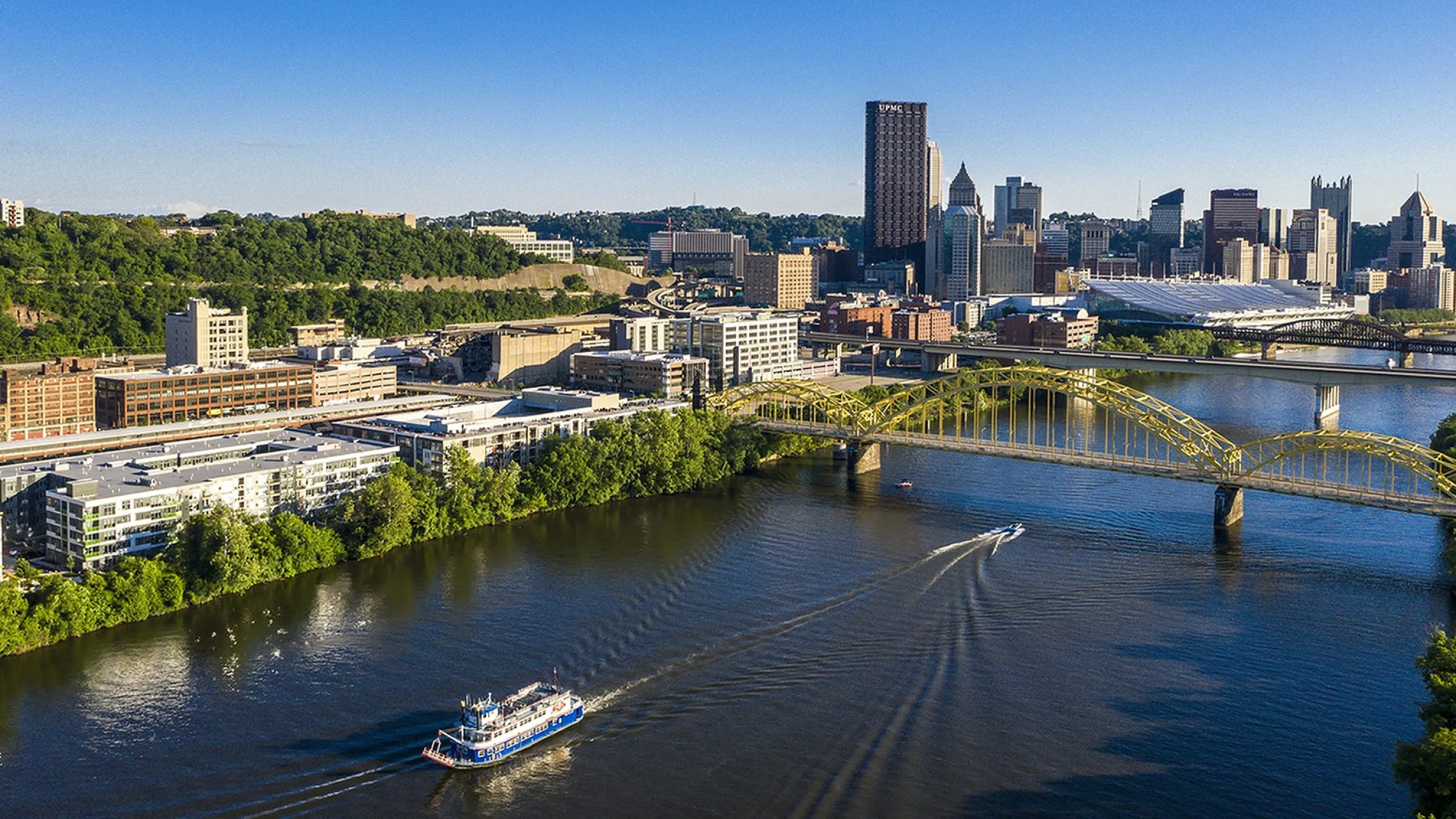 Breathtaking aerial view of a vibrant cityscape with lush greenery, iconic bridges, and tranquil riverfront living.