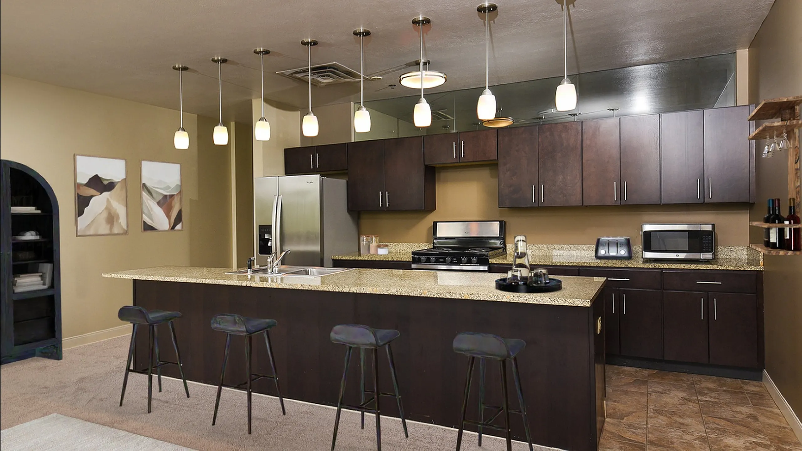 Modern kitchen featuring sleek dark wood cabinetry, elegant granite countertops, and stylish pendant lighting over a spacious breakfast bar.