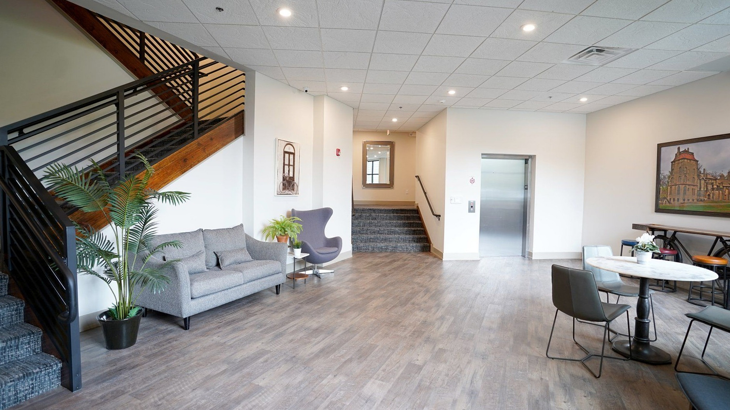 Modern apartment lobby with elegant seating area, vibrant plants, and sleek elevator access.