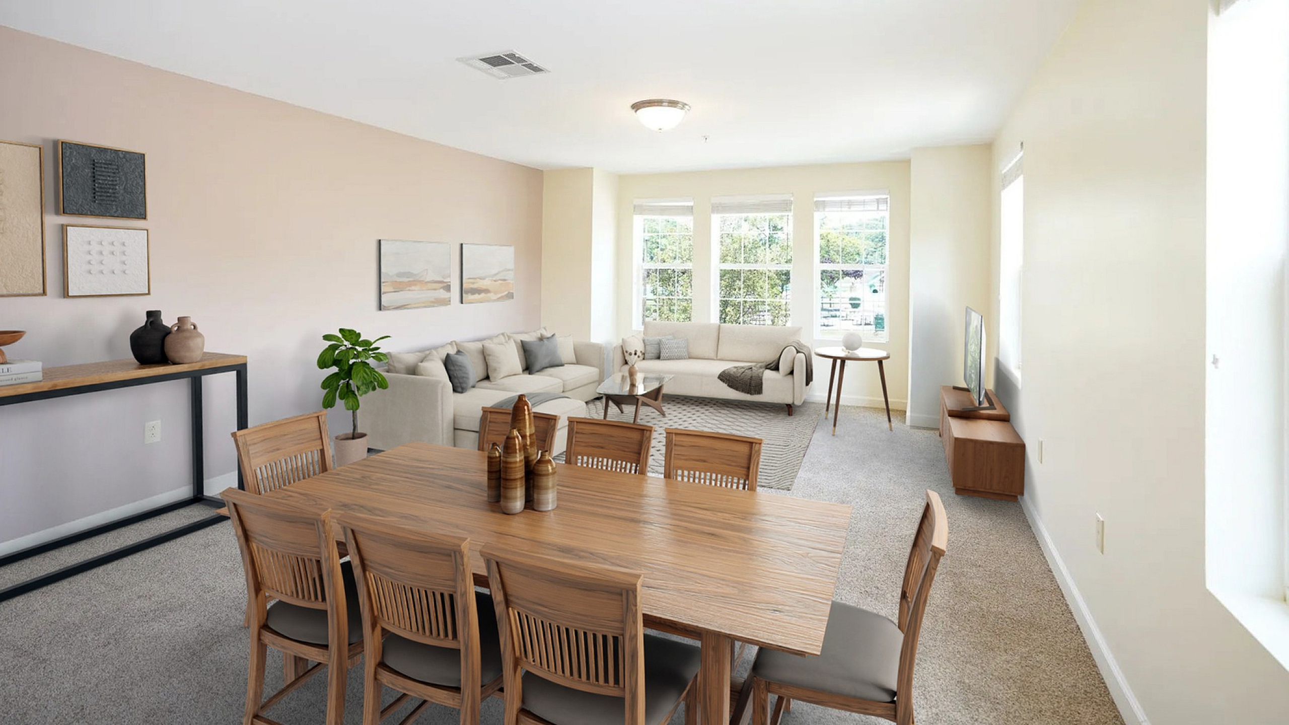 Bright and inviting living room with plush beige sofas, sleek wooden dining set, and large windows providing abundant natural light.