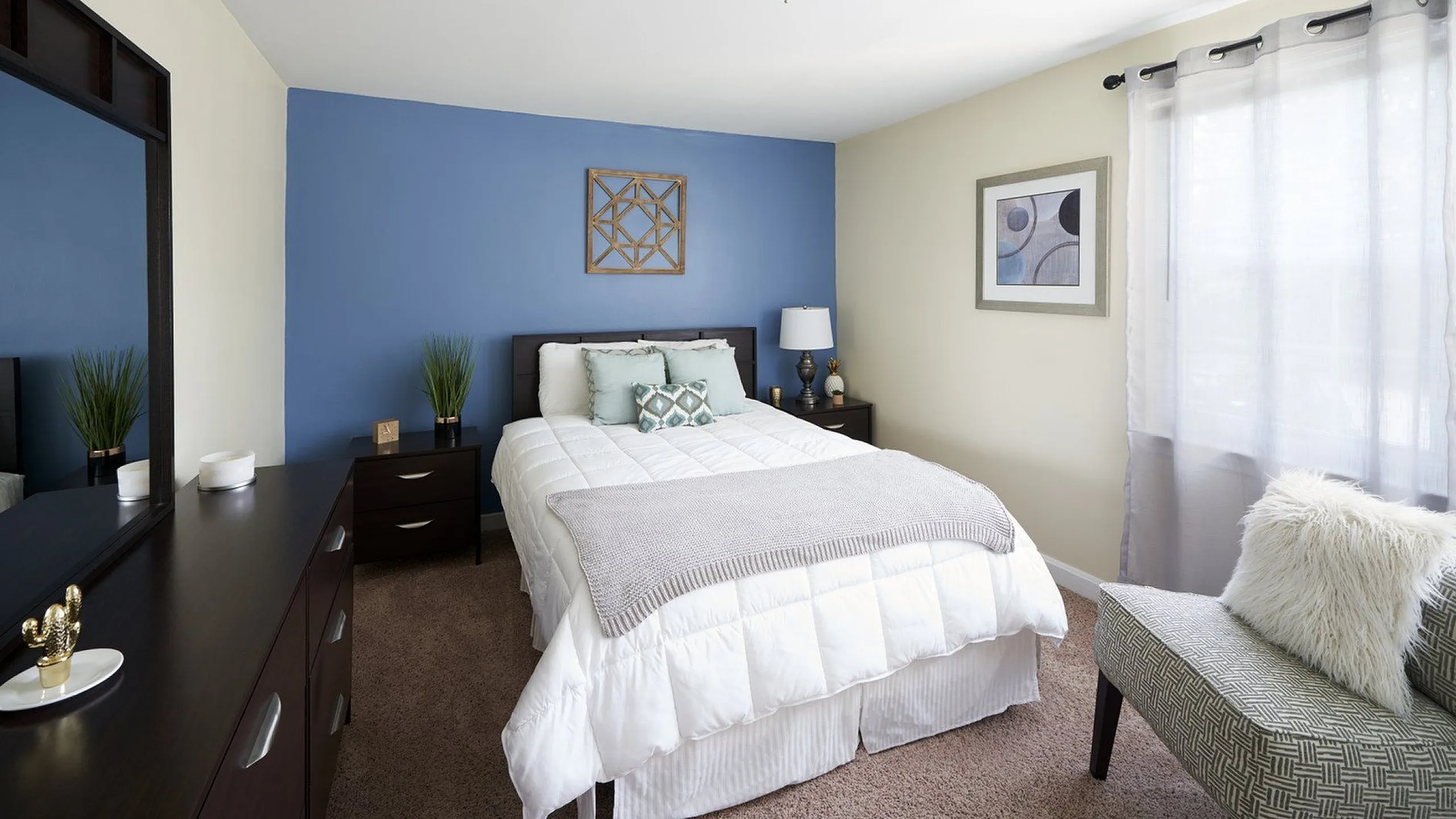 Elegant bedroom featuring a plush white bed, soft blue accent wall, and natural light through sheer curtains.