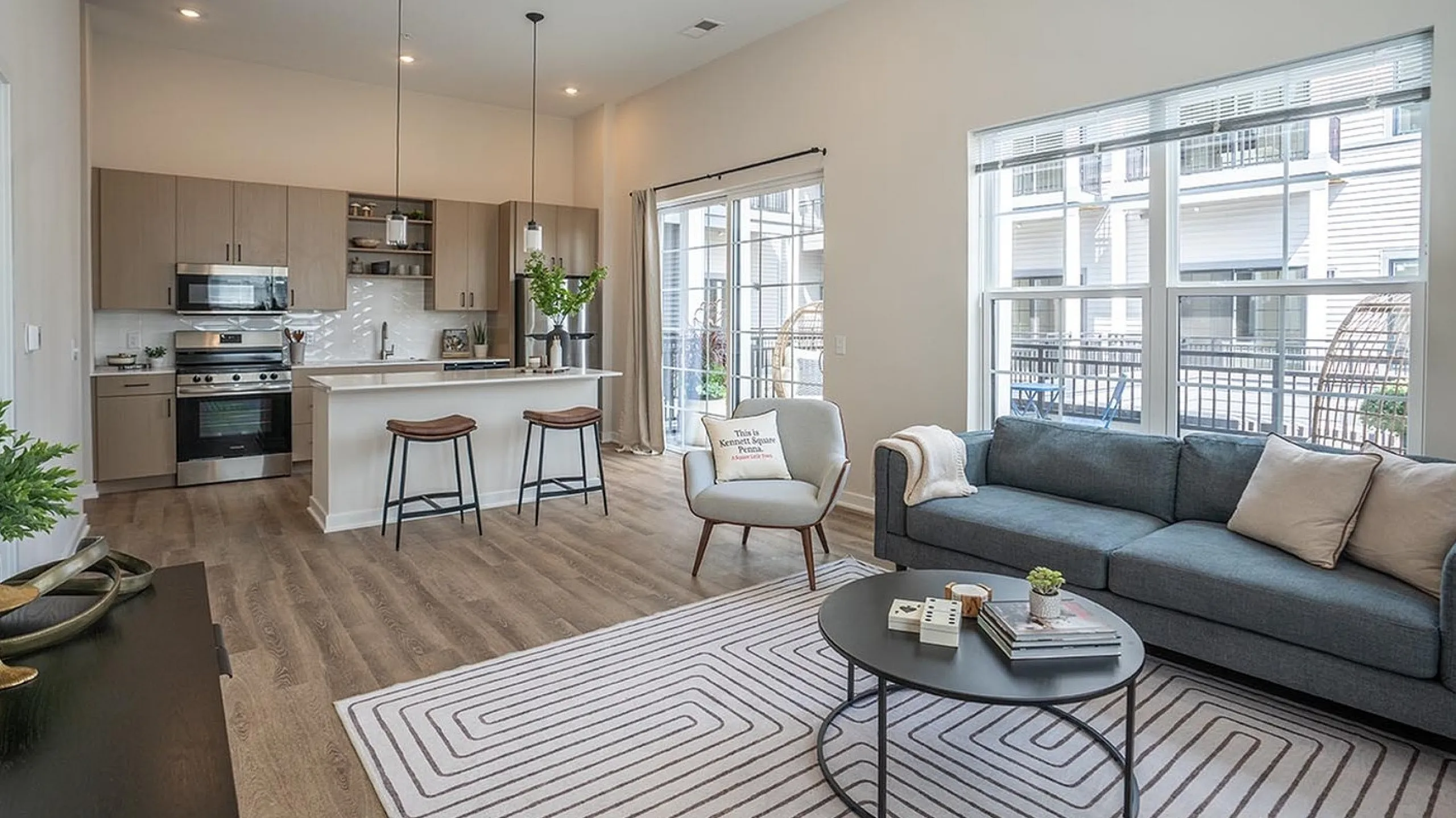 Modern open-concept living space with chic kitchen, stylish seating, and abundant natural light from large windows.