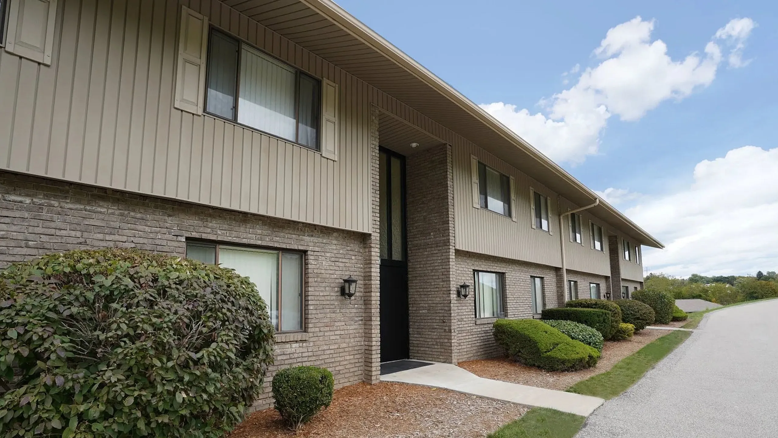 Charming apartment exterior with well-maintained landscaping and inviting walkway, ideal for a serene living experience.