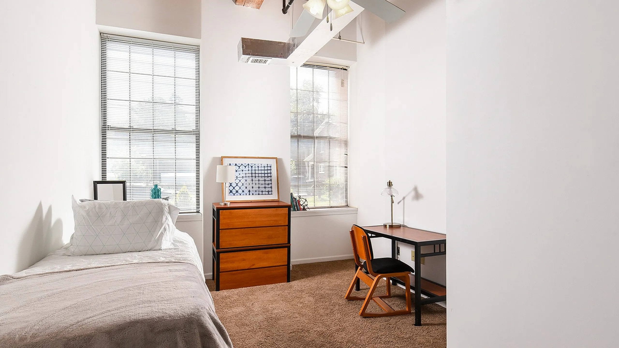 Bright and inviting bedroom with large windows, cozy single bed, stylish desk area, and modern decor, perfect for a tranquil workspace.