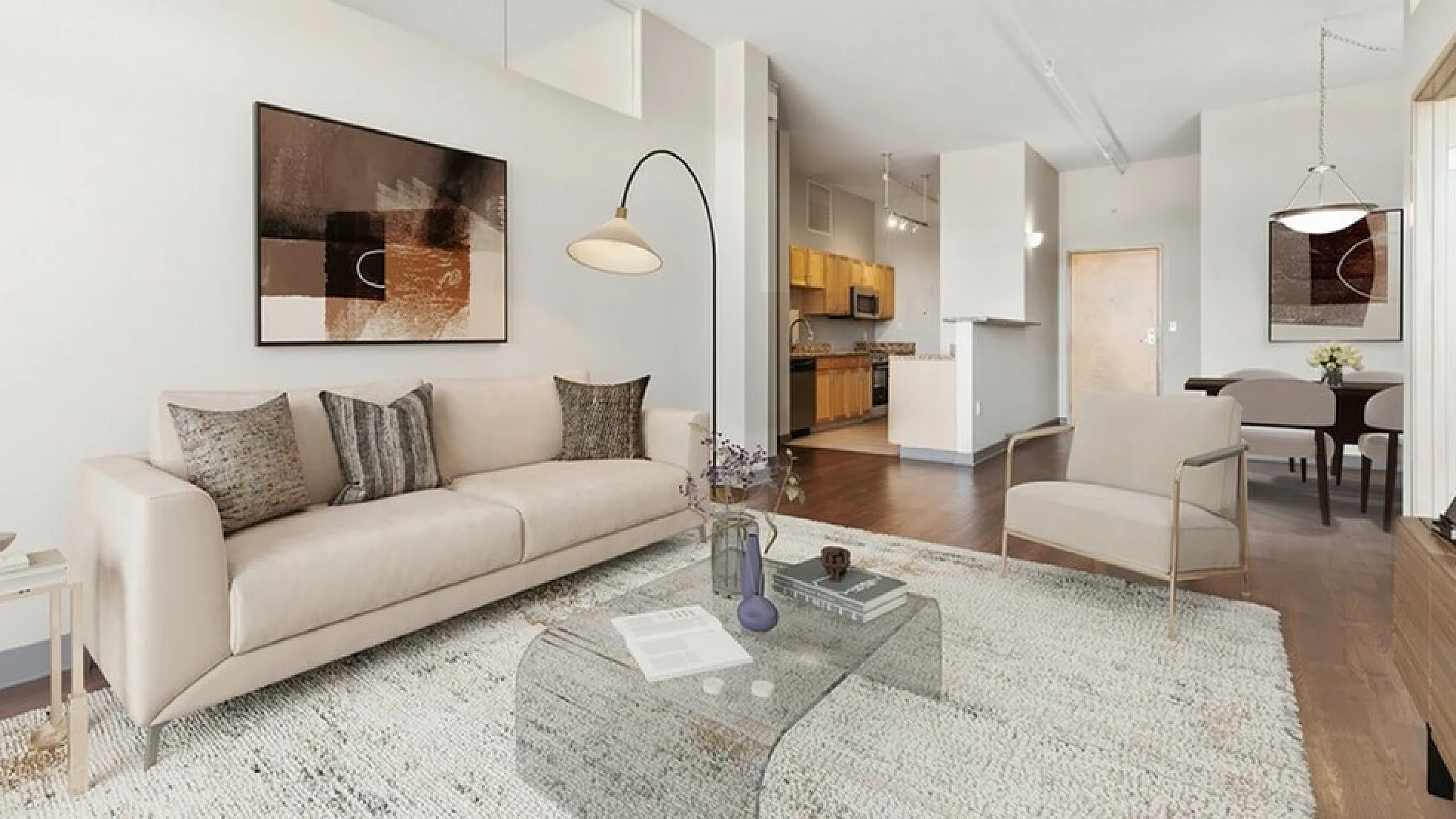 Modern open-plan living room with elegant decor, featuring a cozy sofa, stylish armchair, and a sleek glass table, seamlessly flowing into a spacious kitchen and dining area.