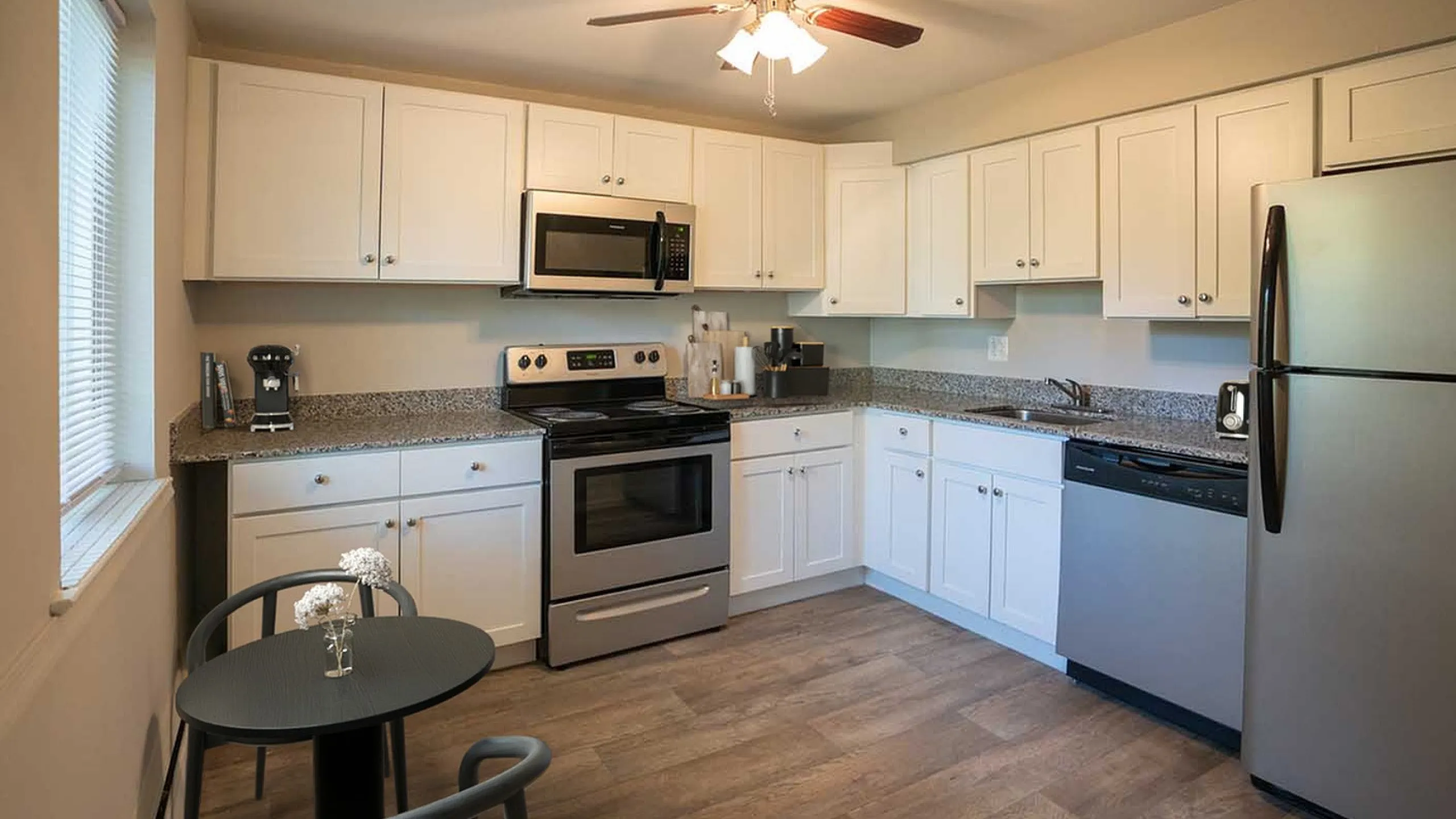 Modern kitchen with stainless steel appliances, white cabinetry, and elegant granite countertops.
