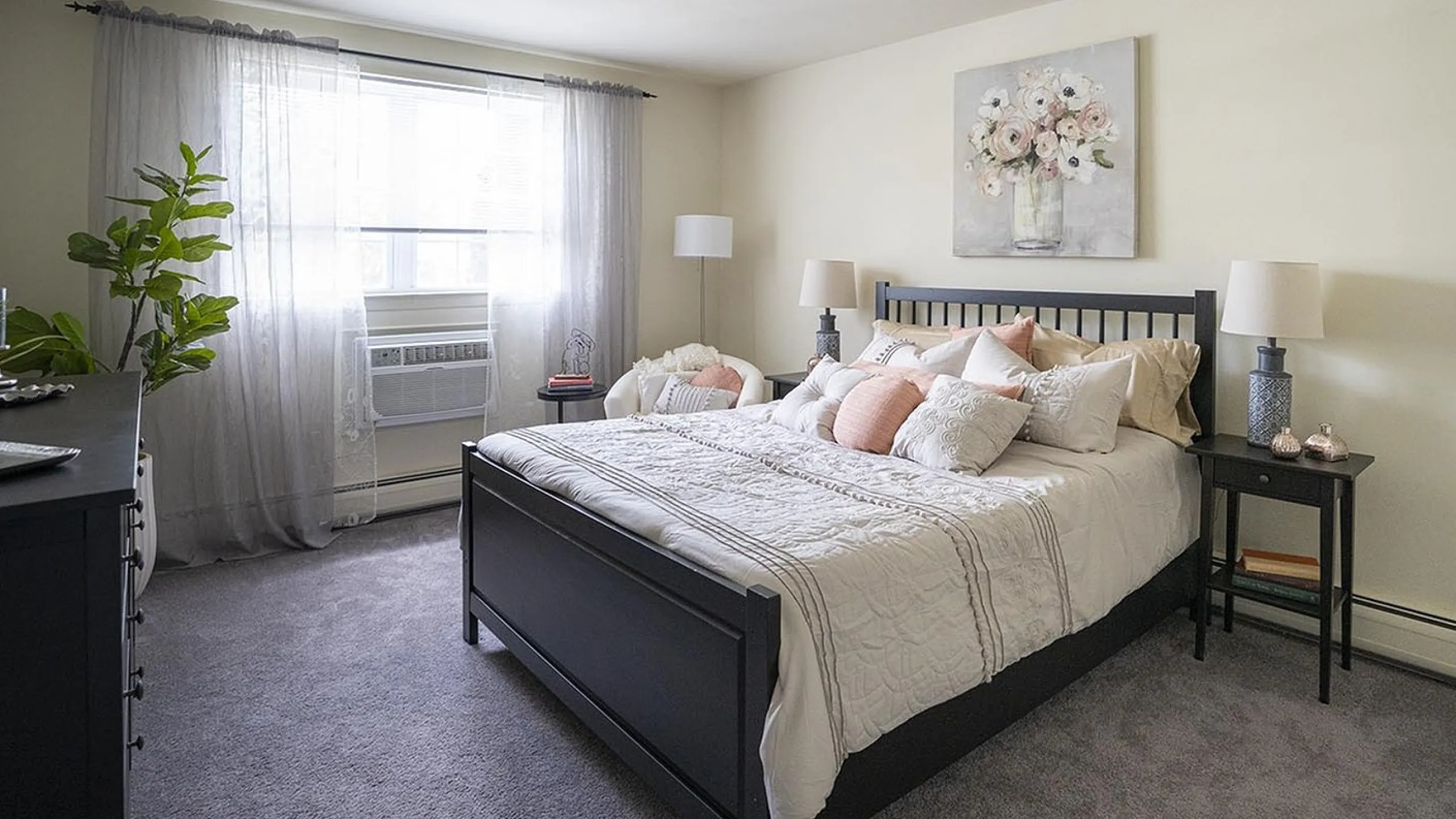 Inviting bedroom with elegant decor, featuring a plush bed, soft lighting, and a bright window with sheer curtains.
