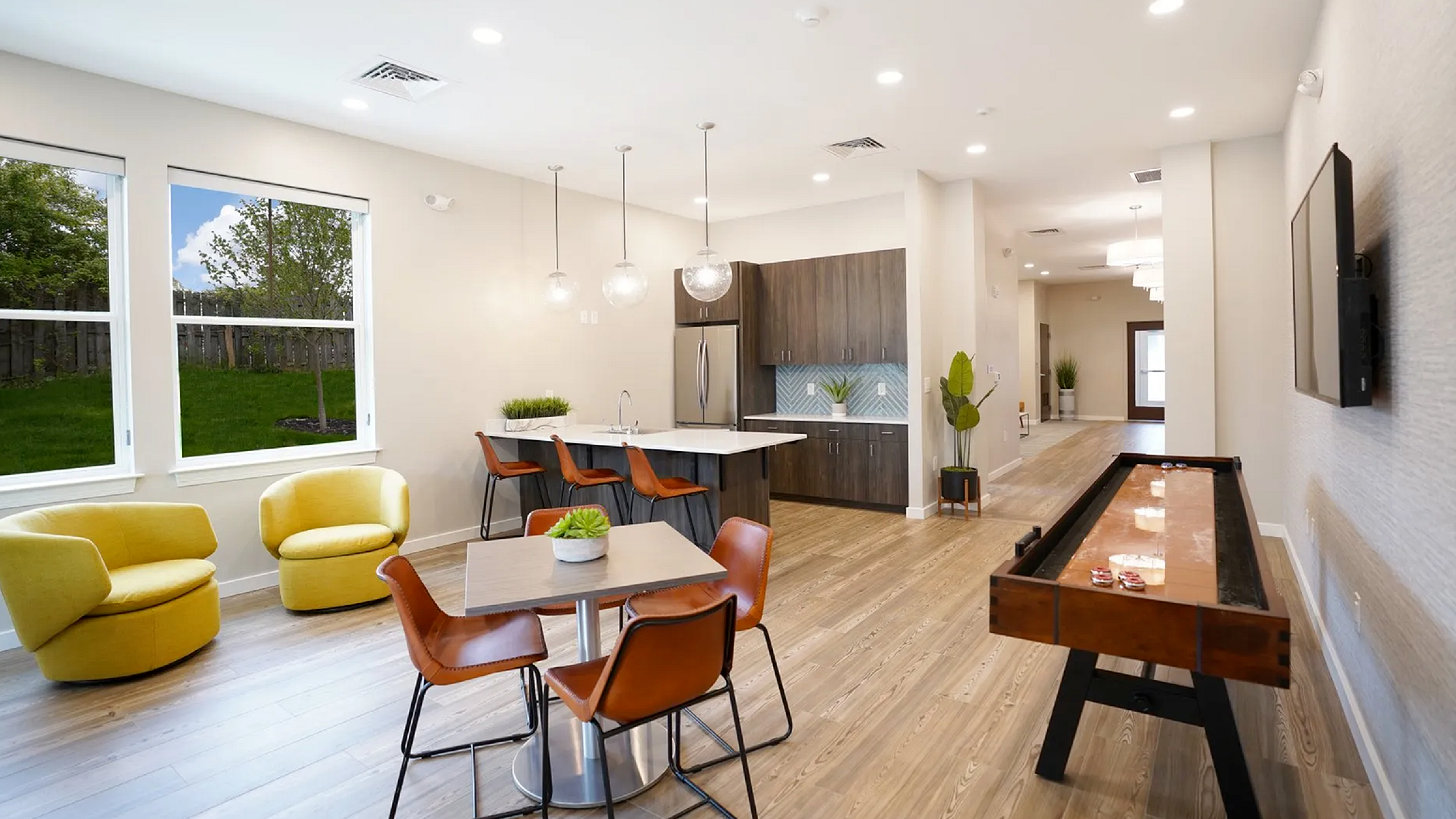 Contemporary open-concept living space with elegant kitchen island, stylish seating, and game table, flooded with natural light.