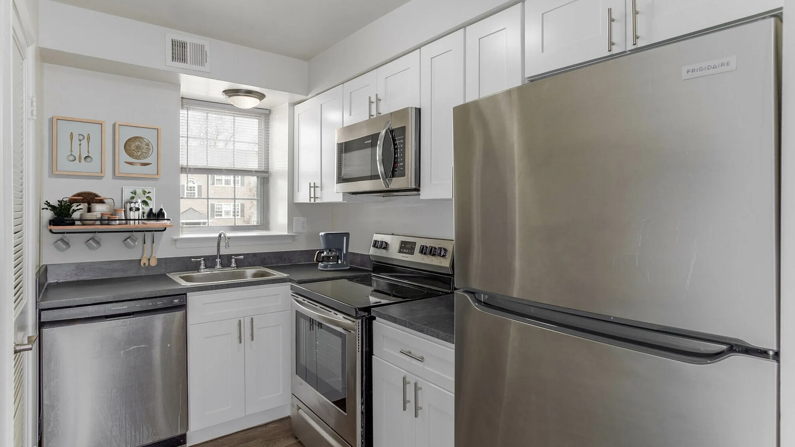 Modern kitchen with stainless steel appliances, sleek white cabinets, and elegant wood flooring.