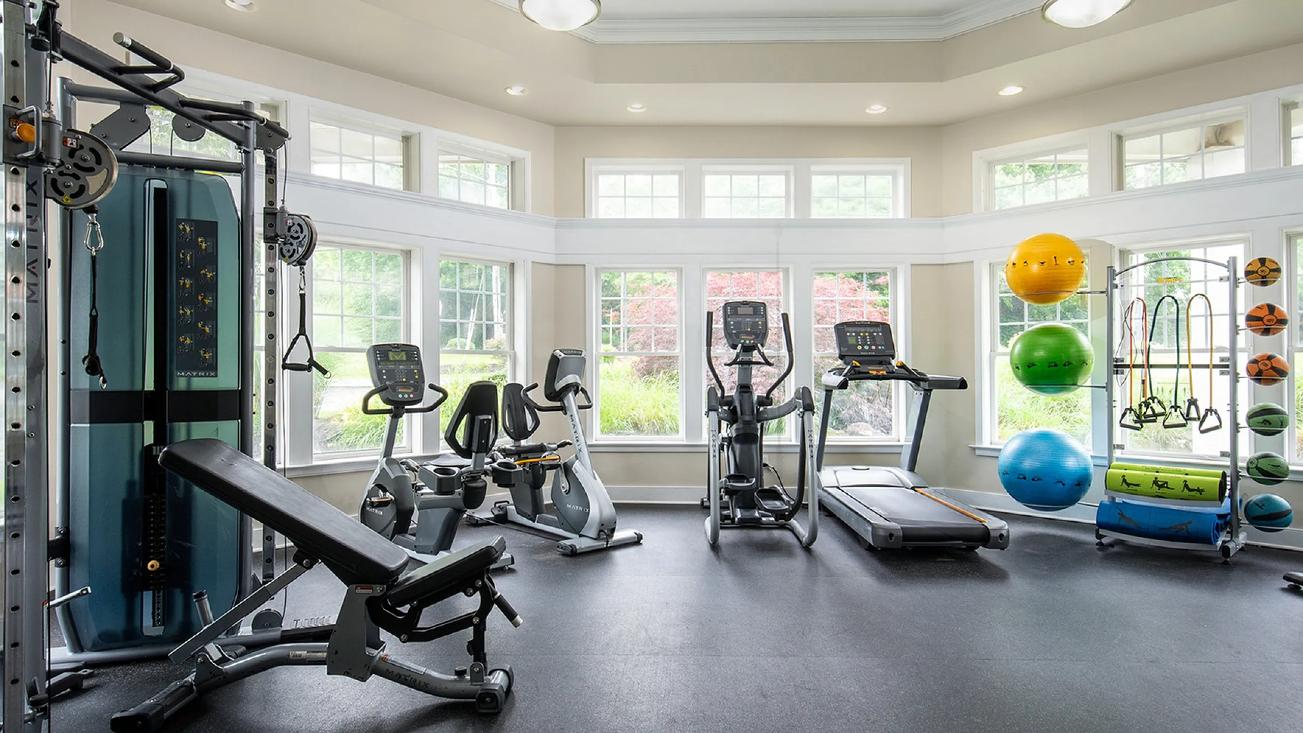 Bright and spacious home gym featuring modern exercise equipment, large windows providing natural light, and vibrant fitness accessories.