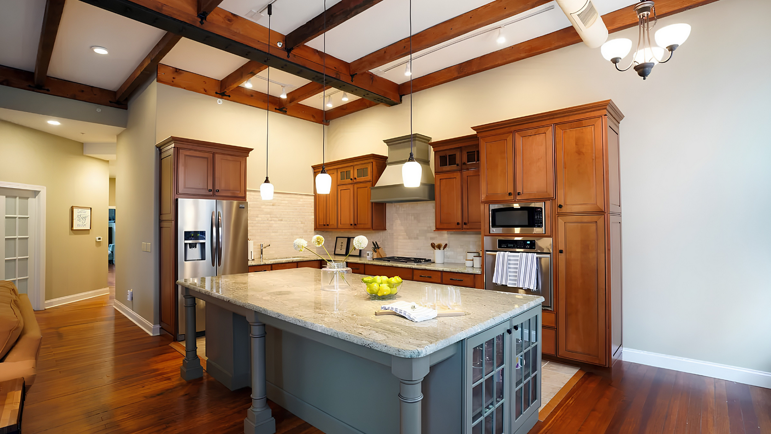 Inviting kitchen with warm wood cabinetry, modern stainless steel appliances, and elegant pendant lighting over a large, stylish island.
