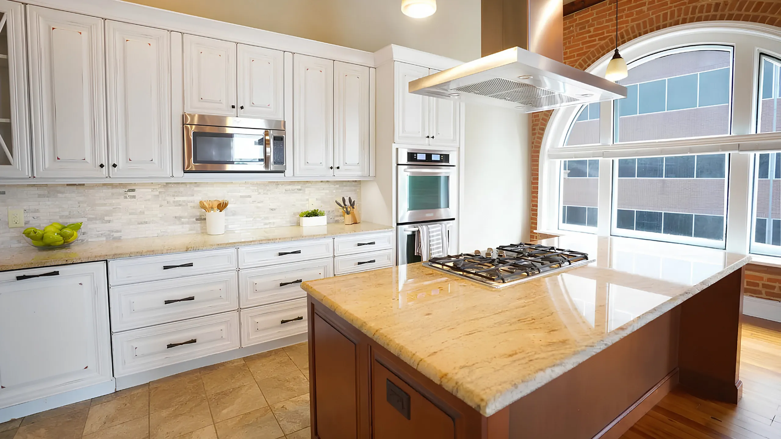 Elegant kitchen with white cabinetry, granite countertops, and large arched window for natural light.