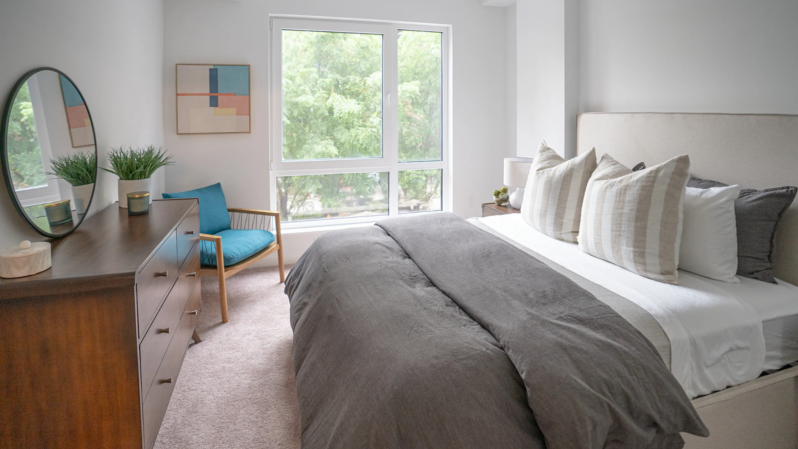 Bright, modern bedroom with large windows, stylish decor, and a cozy reading nook.