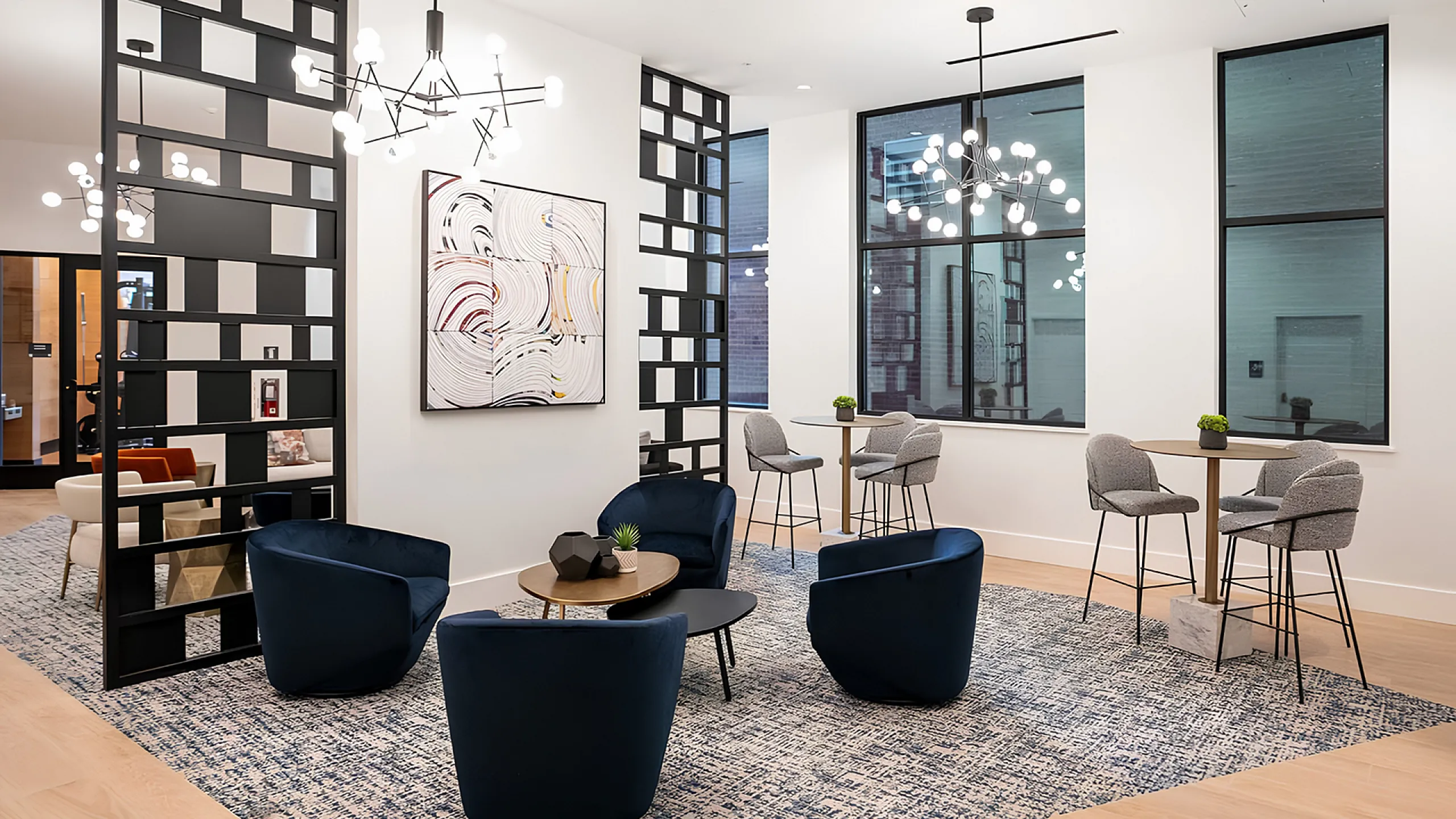 Chic and modern lounge area with stylish black lattice partitions, elegant blue chairs, and contemporary lighting fixtures.